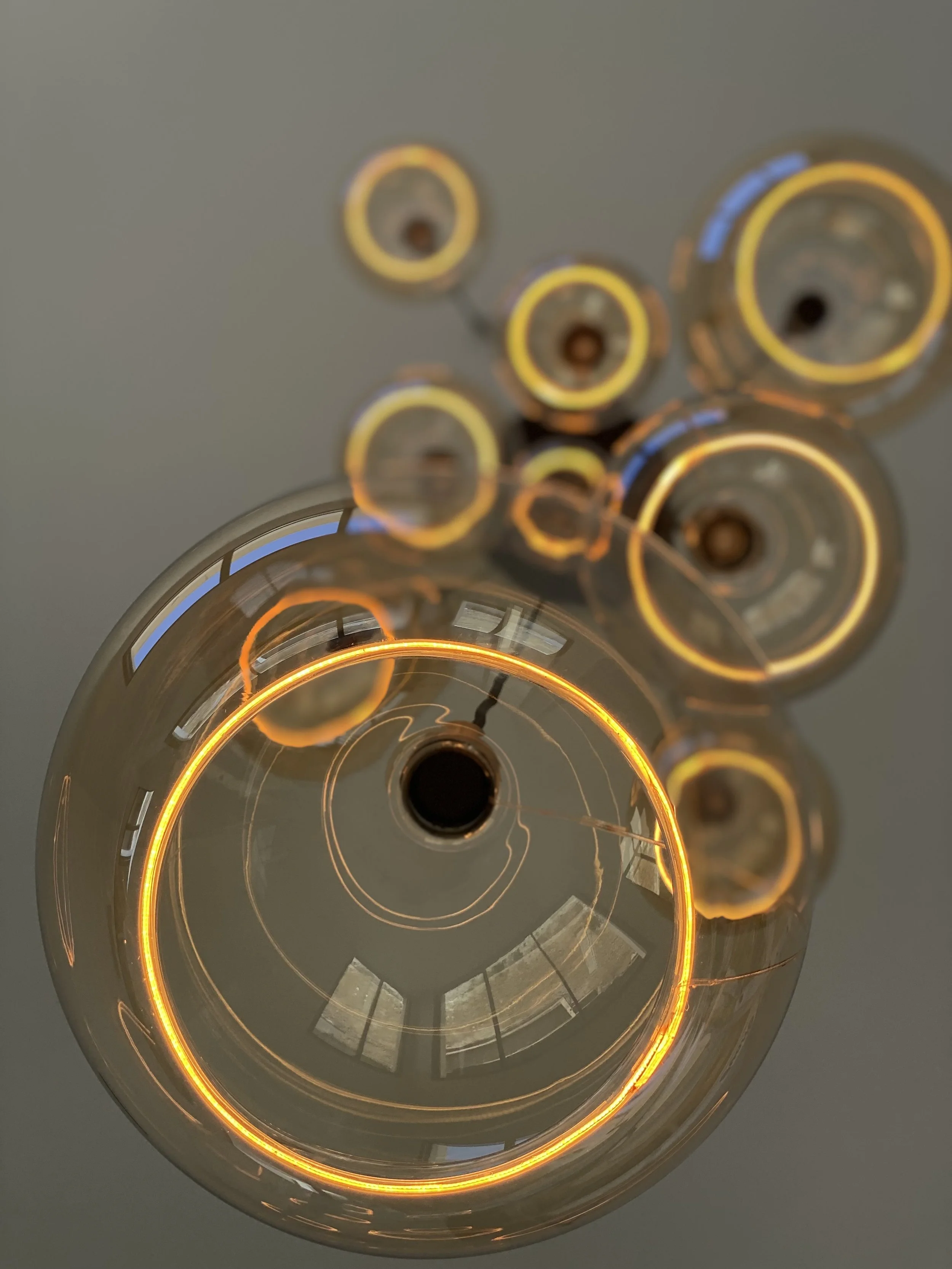 Plafonnier moderne avec ampoules circulaires et anneaux lumineux.