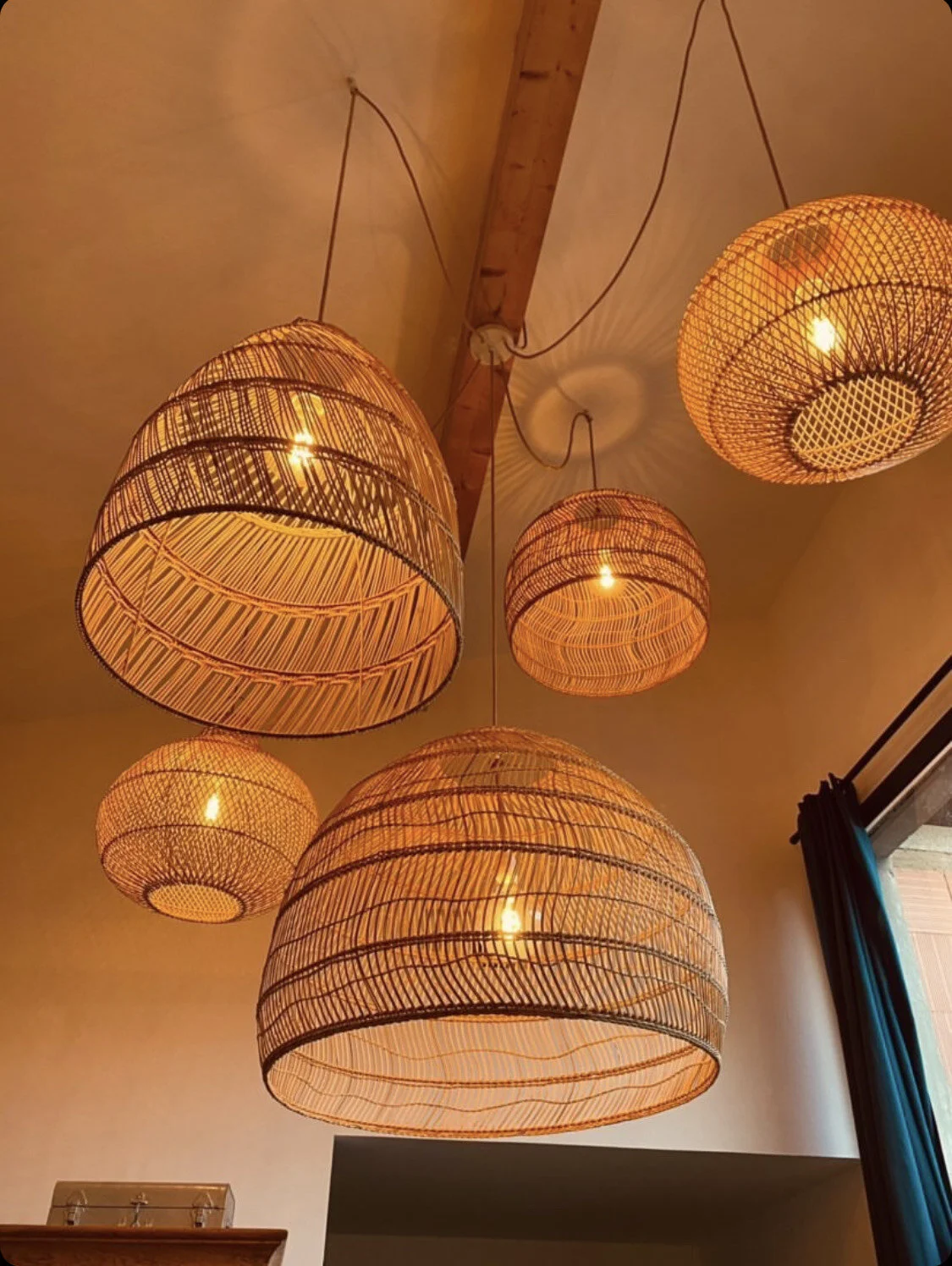 Lampes suspendues en rotin illuminées au plafond d'une pièce.