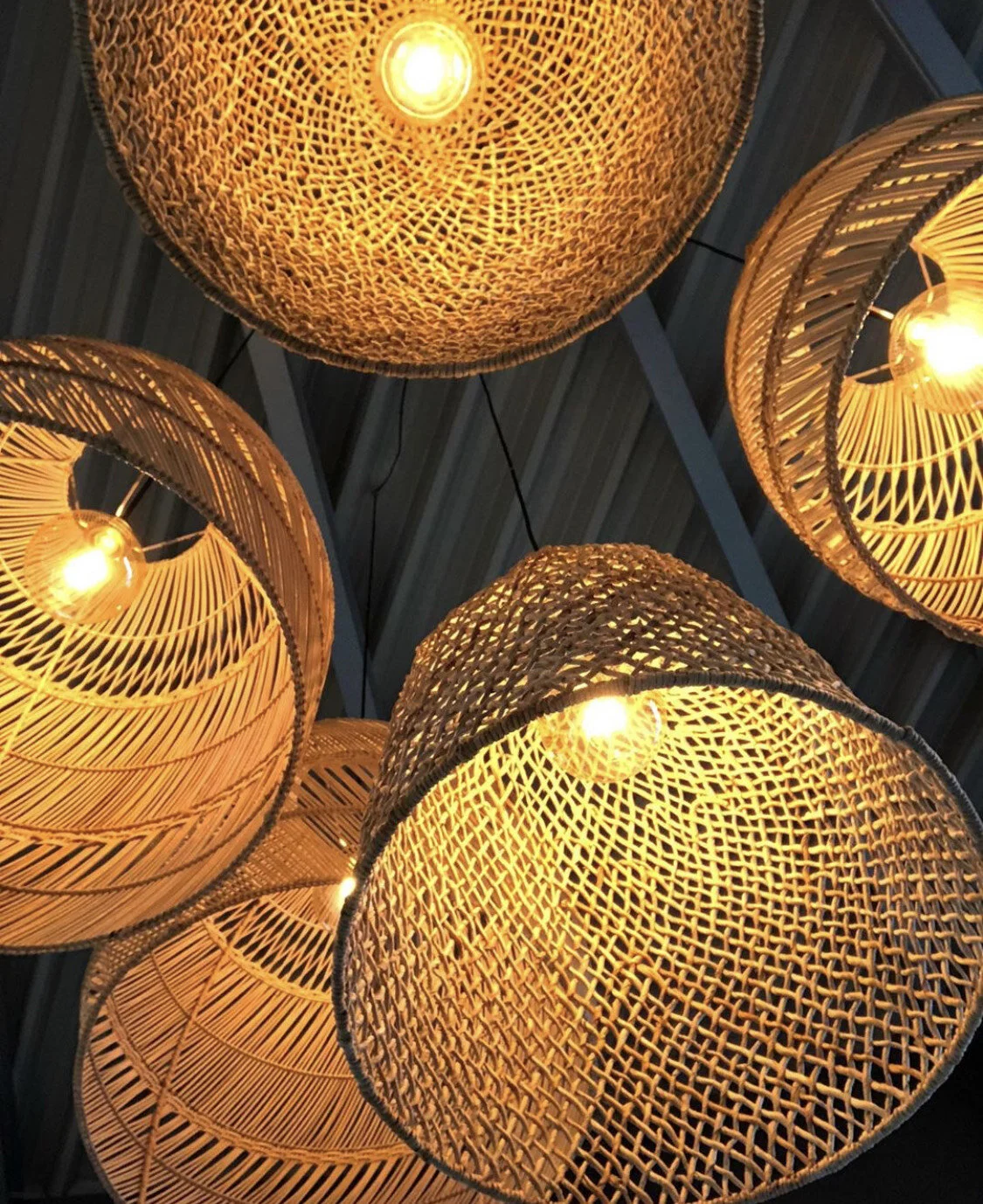 Suspensions lumineuses en osier avec ampoules allumées, vue d'en bas.