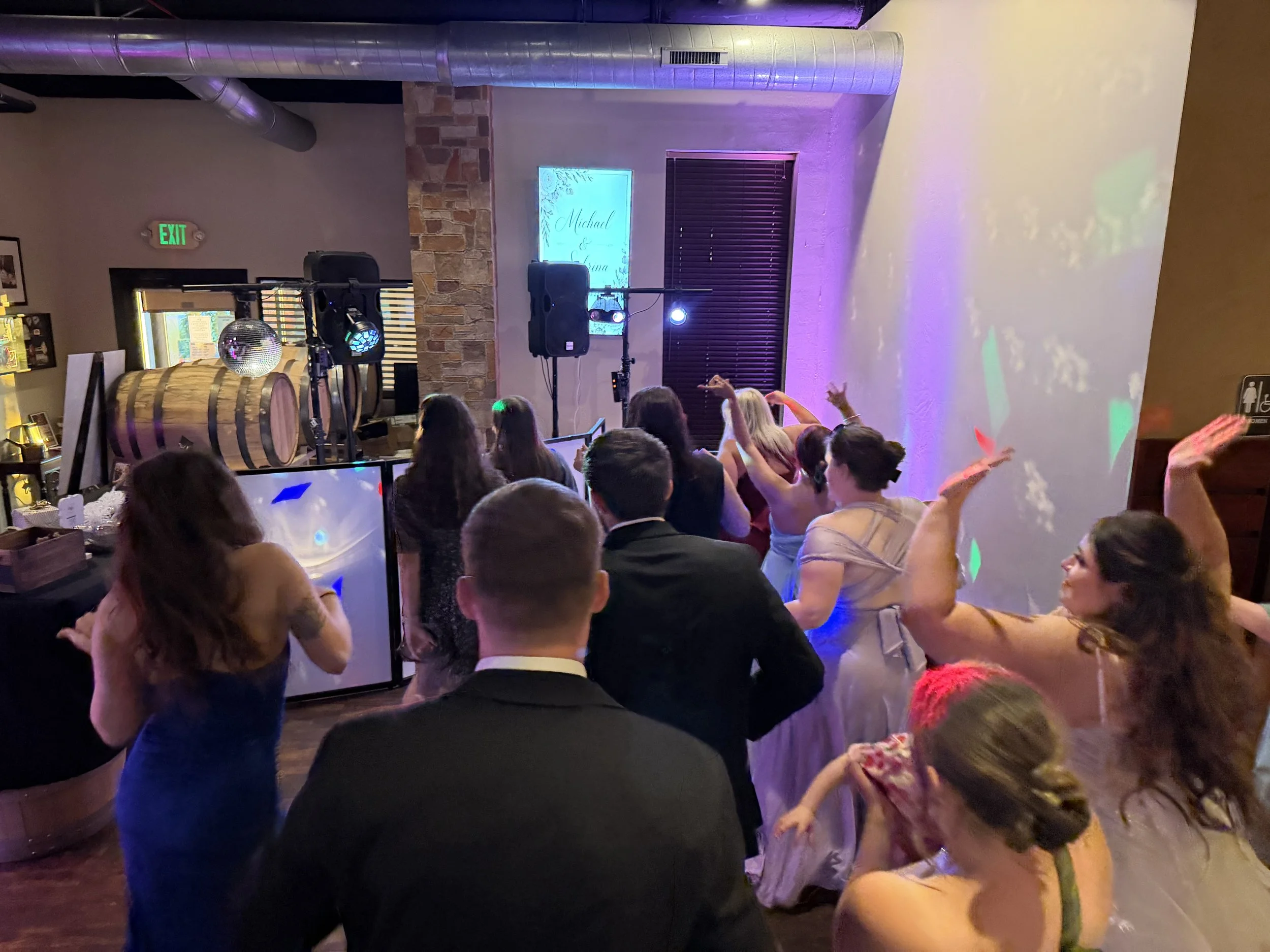 People dancing and celebrating at a wedding reception with lighting and a DJ setup