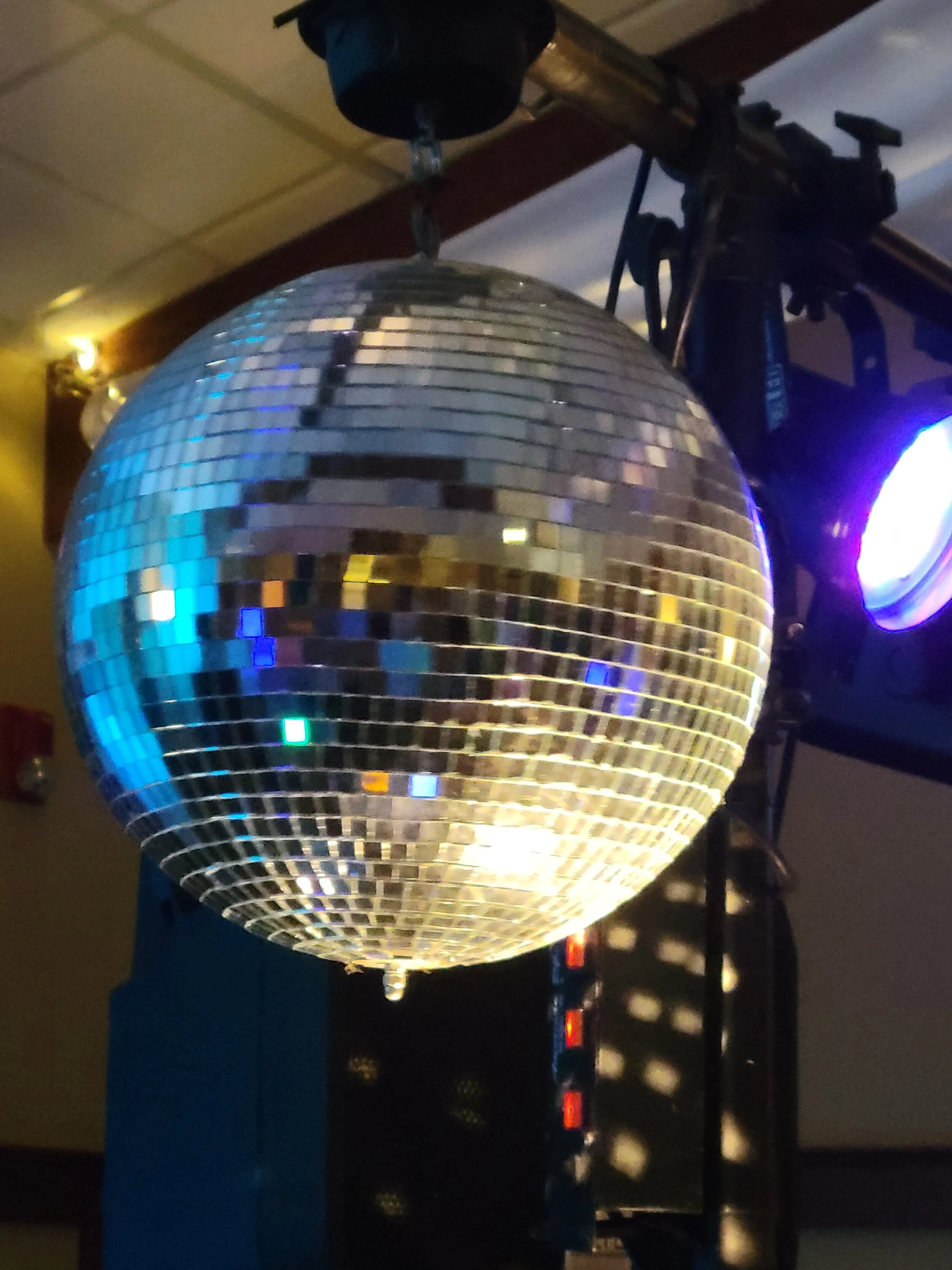 Disco ball hanging from a ceiling with colorful lights reflecting on it