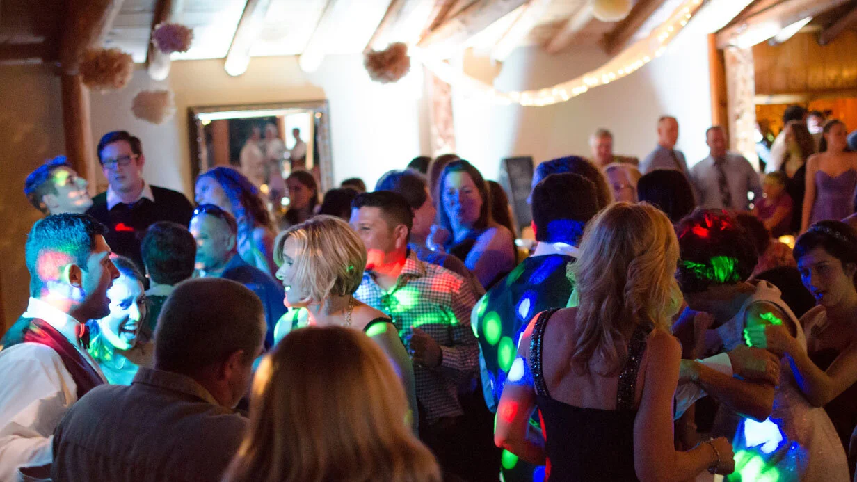 A lively indoor party with people dancing under colorful lights.