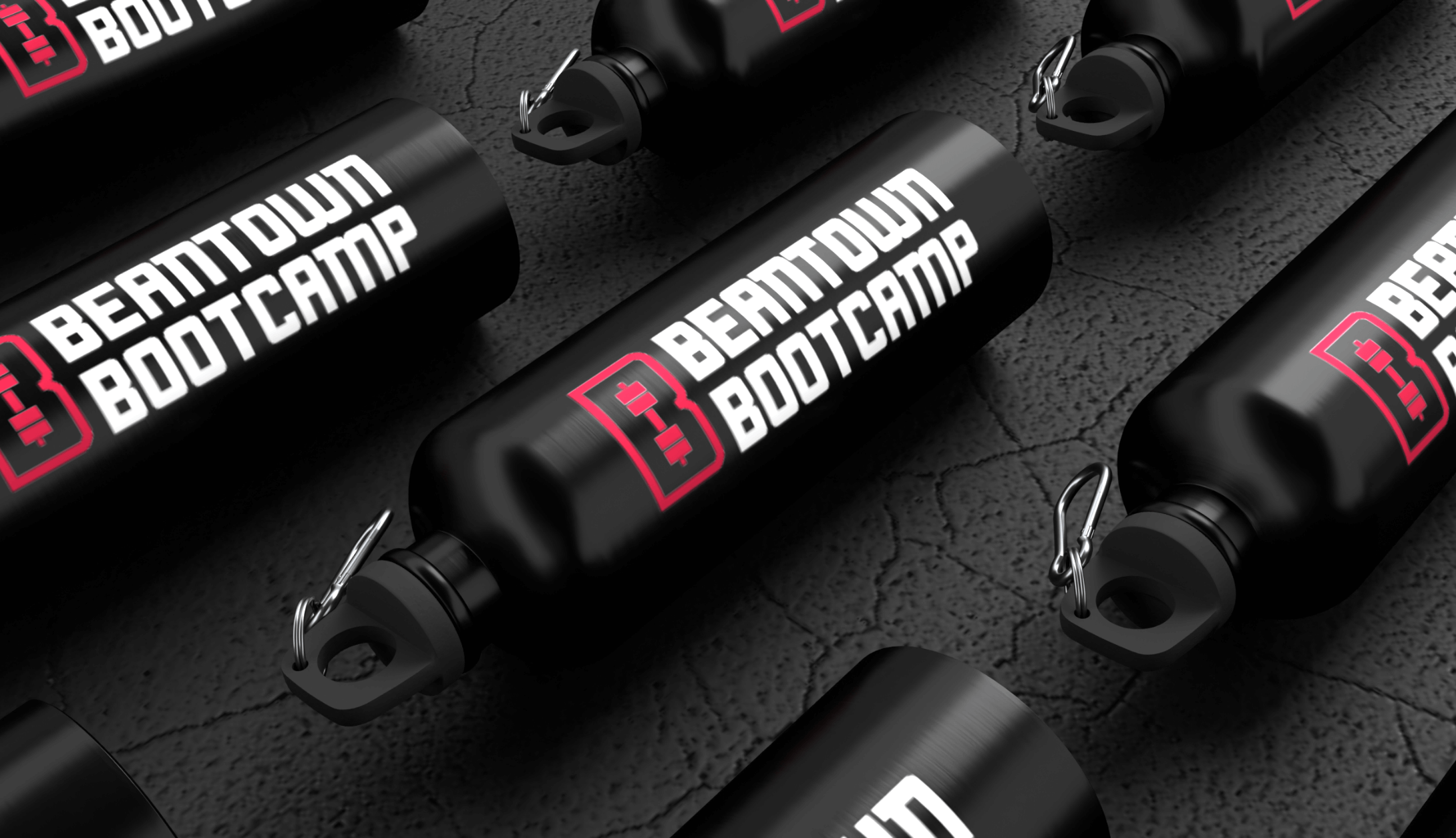 Several black workout water bottles labeled 'Beantown Bootcamp' with red and white text, lying on a dark textured surface.