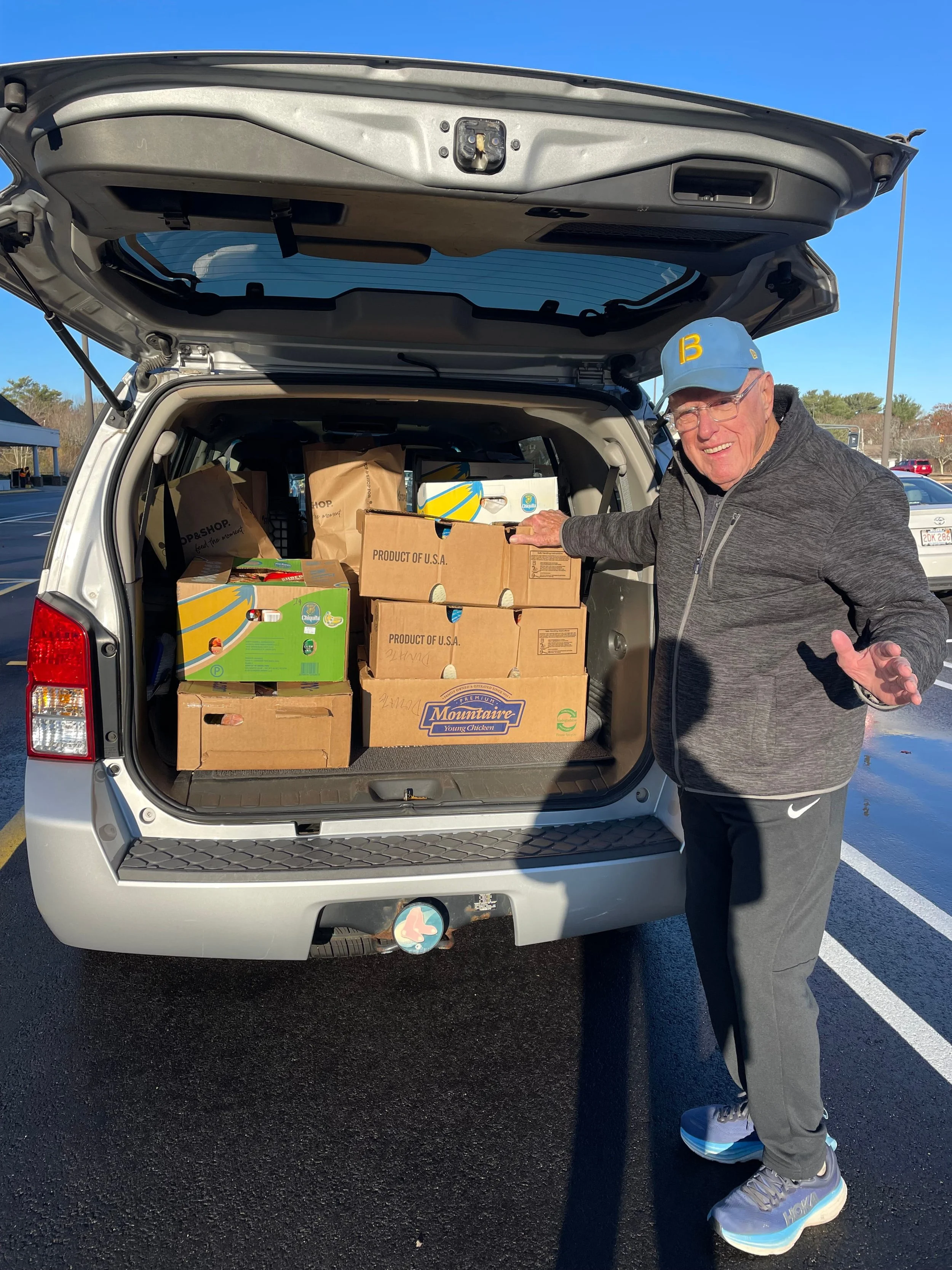 person stands in front of a car load of food