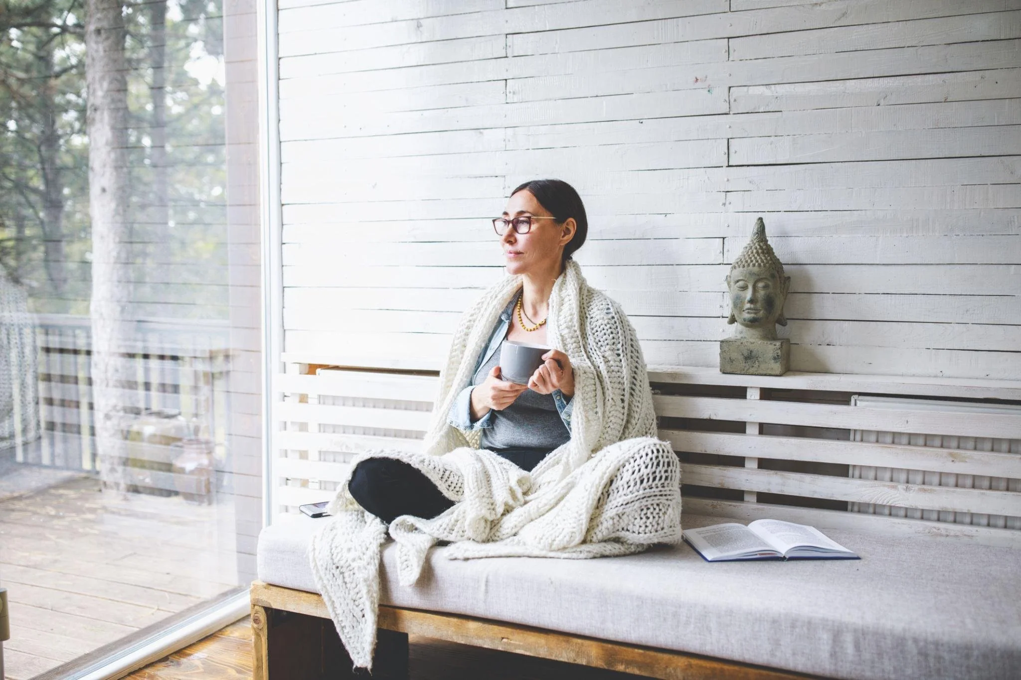 Woman sitting by a window in a calm, reflective moment, representing mindfulness and everyday awareness