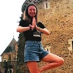 Joey in a tree pose in front of a stone building