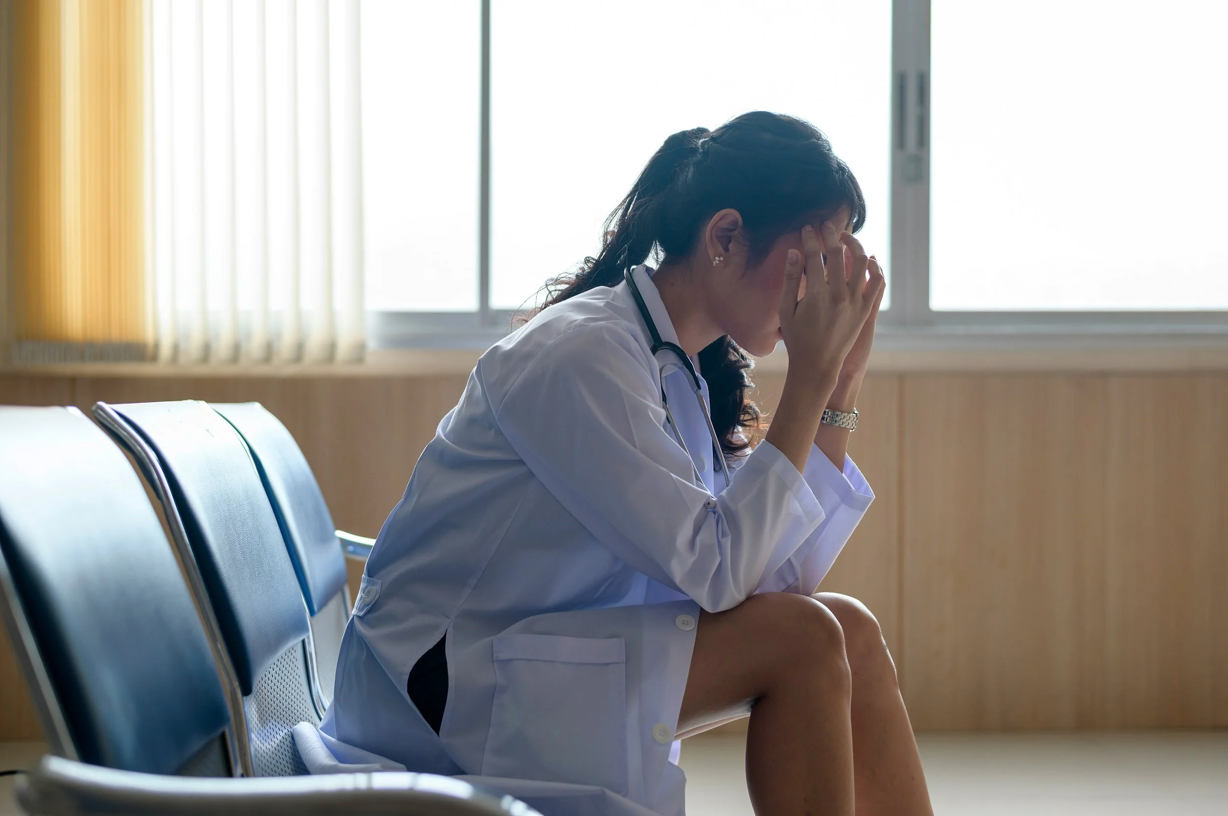 Hospital employee stressed out with face cradled in hands