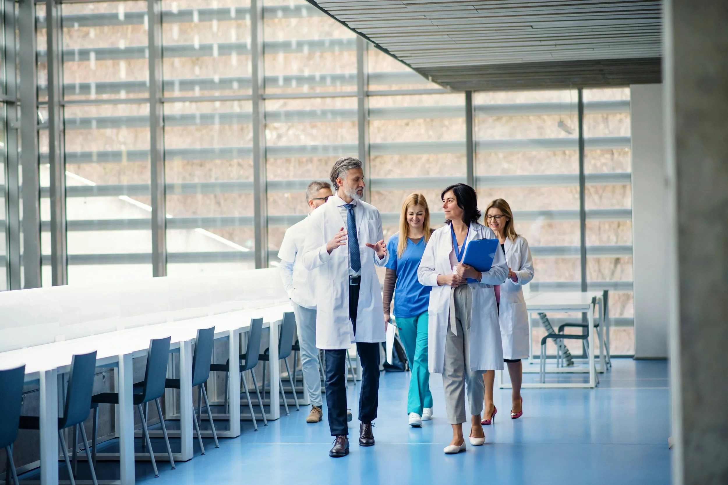 Team of healthcare professionals walking through a hallway having a lighthearted conversation