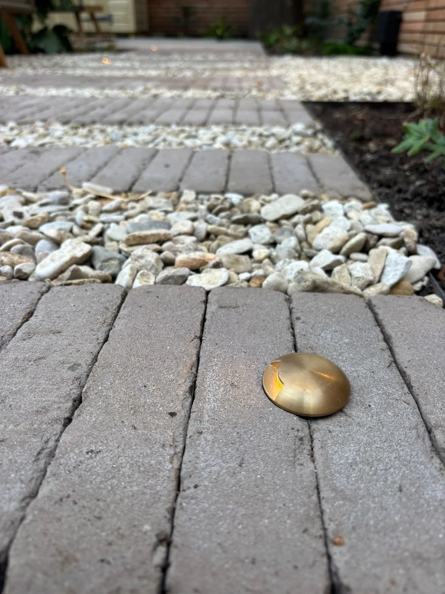 Brass light fitting in clay paver path