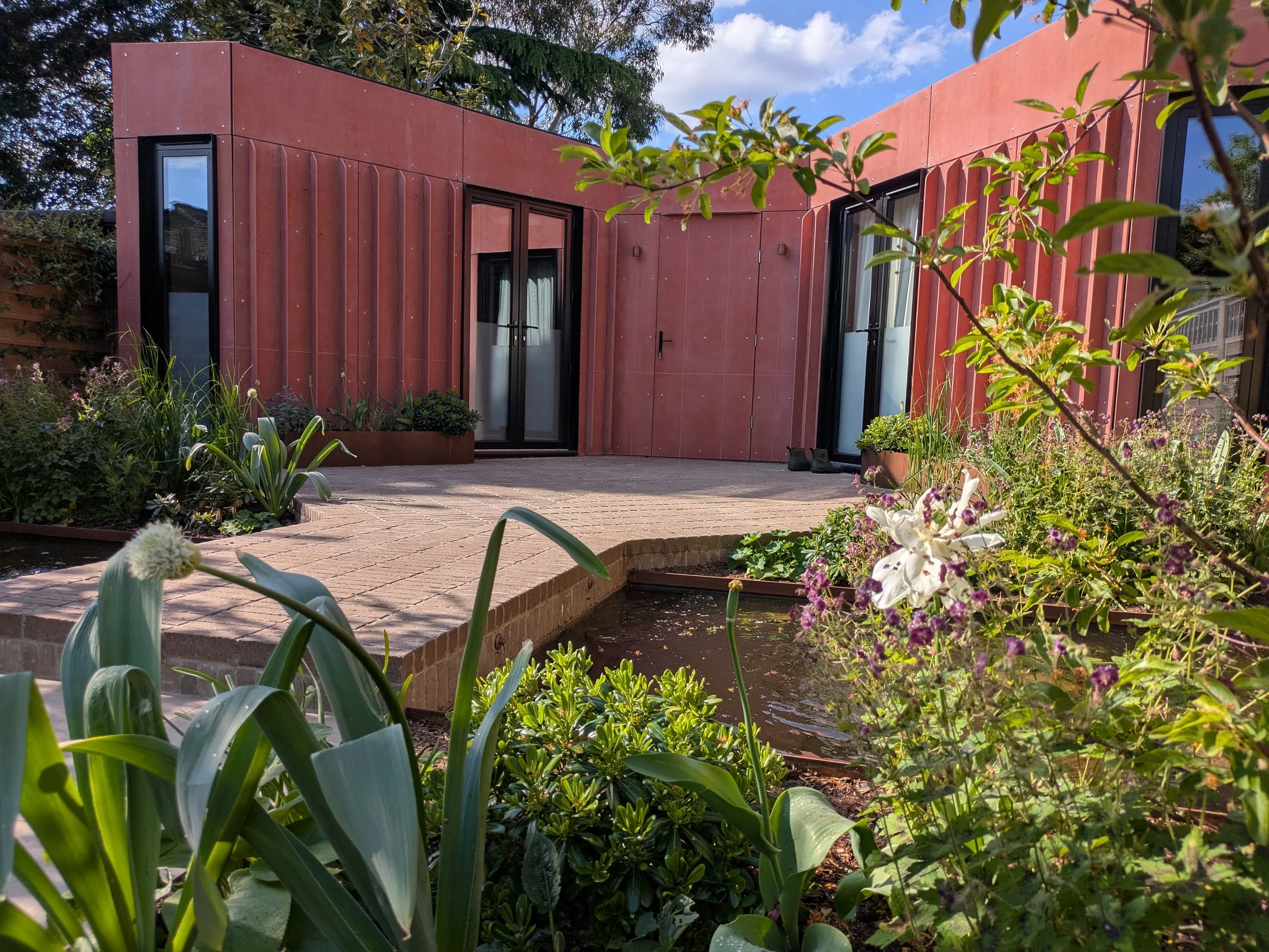 Bespoke garden room with clay paver terrace and ponds
