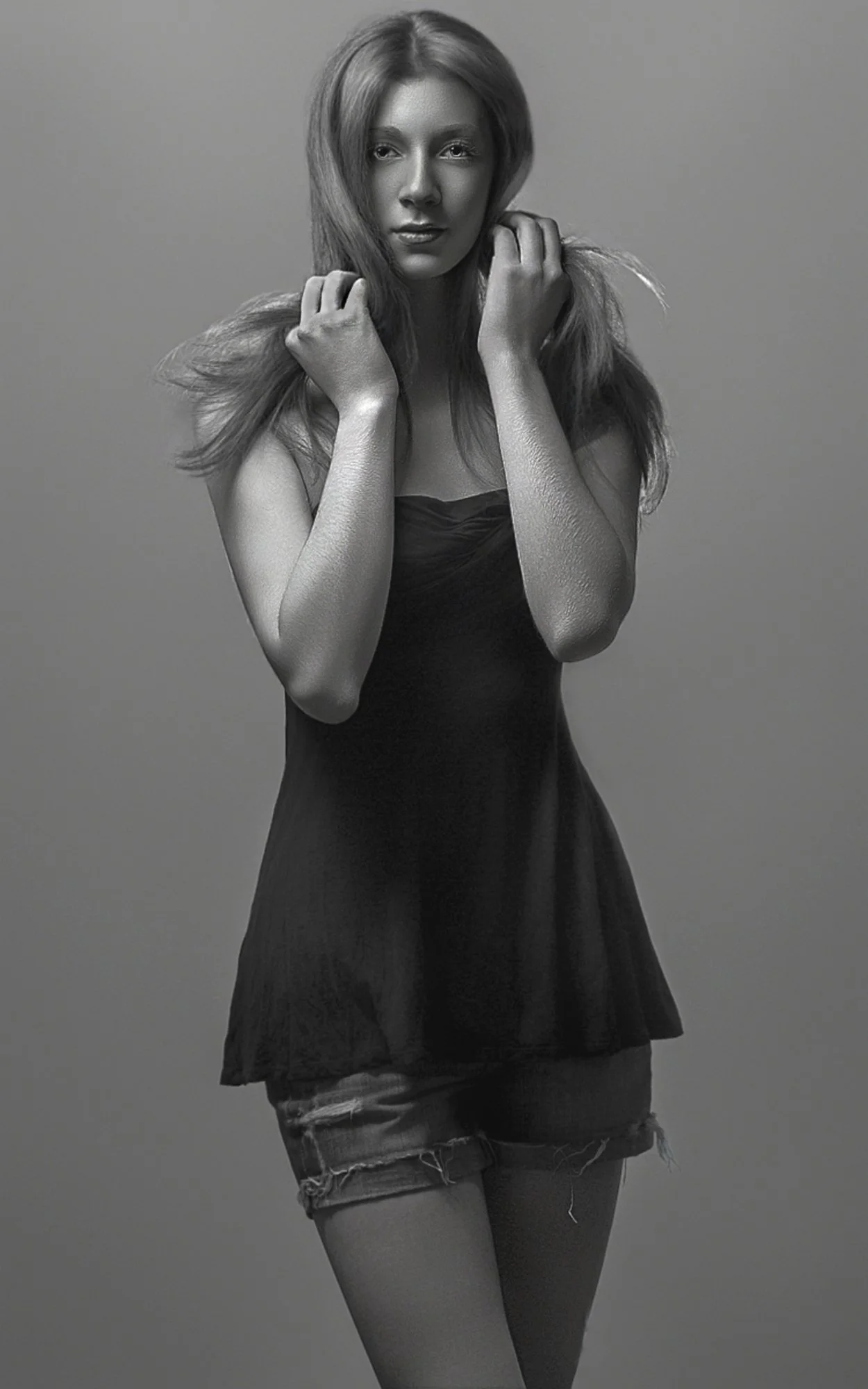 Black and white photo of a woman with long hair wearing a dark top and ripped denim shorts, posing against a plain background. Best-Fashion-Portrait-Commercial-Business-Headshots-Corporate- photography-Maryland-Washington D.C.-Pennsylvania-Virginia
