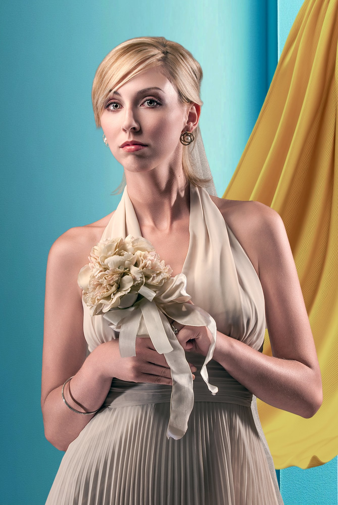 A woman with blonde hair and fair skin wearing a cream-colored, pleated dress and earrings, holding a small bouquet of flowers with ribbons. Best-Fashion-Portrait-Commercial-Business-Headshots-Corporate- photography-Maryland-Washington D.C.-Pennsylva