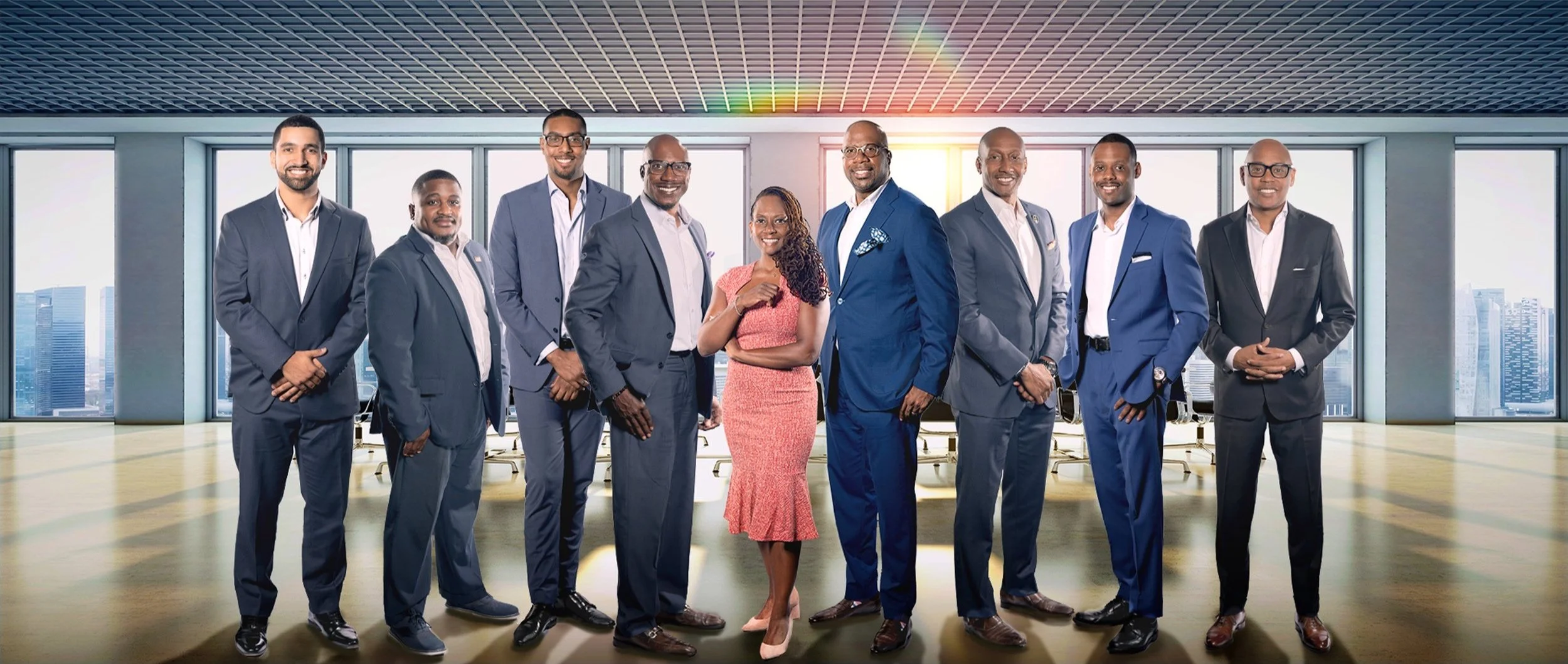 A diverse group of ten professional men and women in business attire standing in a modern office with large windows and city skyline views.