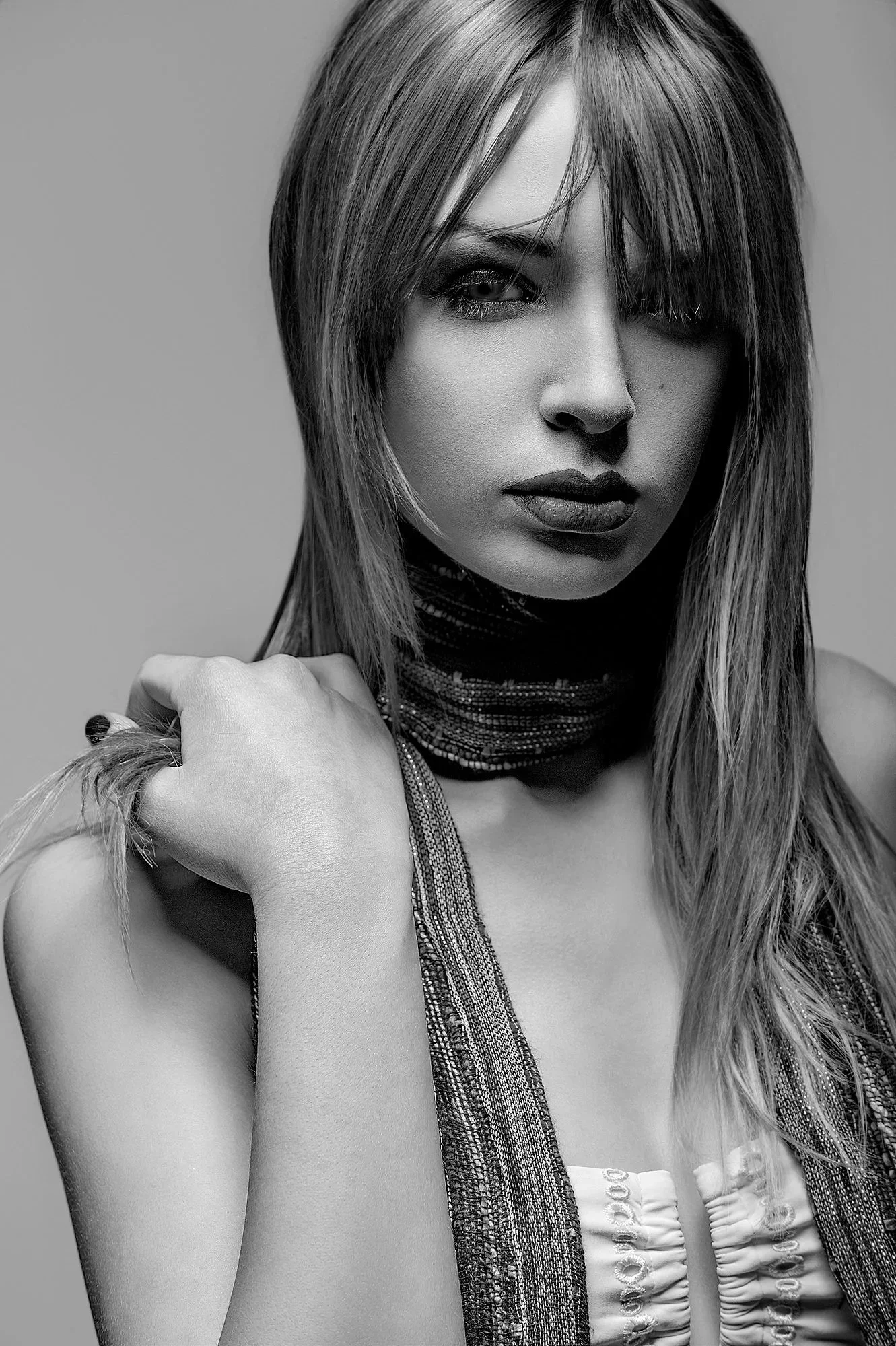 Black and white portrait of a woman with long hair, one eye hidden, wearing a scarf and sleeveless top, with serious expression. Best-Fashion-Portrait-Commercial-Business-Headshots-Corporate- photography-Maryland-Washington D.C.-Pennsylvania-Virginia