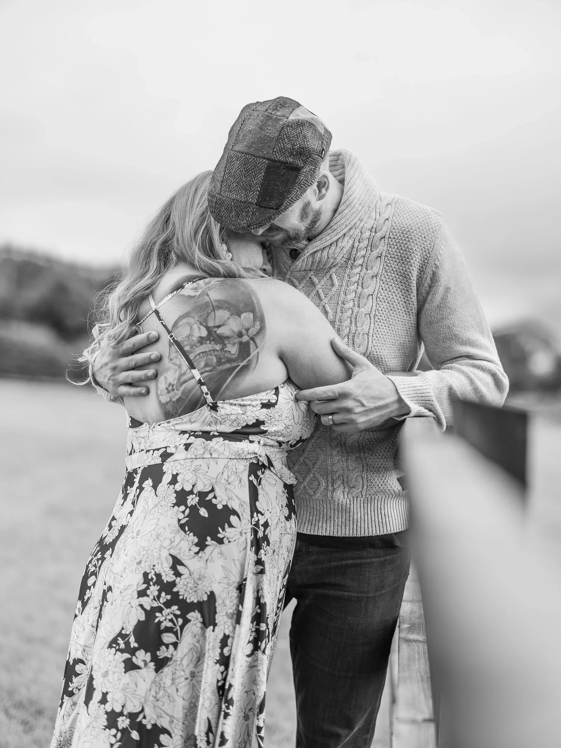 A black and white photo of a couple embracing and touching foreheads outdoors, with blurred background of open sky and landscape. Best-Fashion-Portrait-Commercial-Business-Headshots-Corporate- photography-Maryland-Washington D.C.-Pennsylvania-Virgini