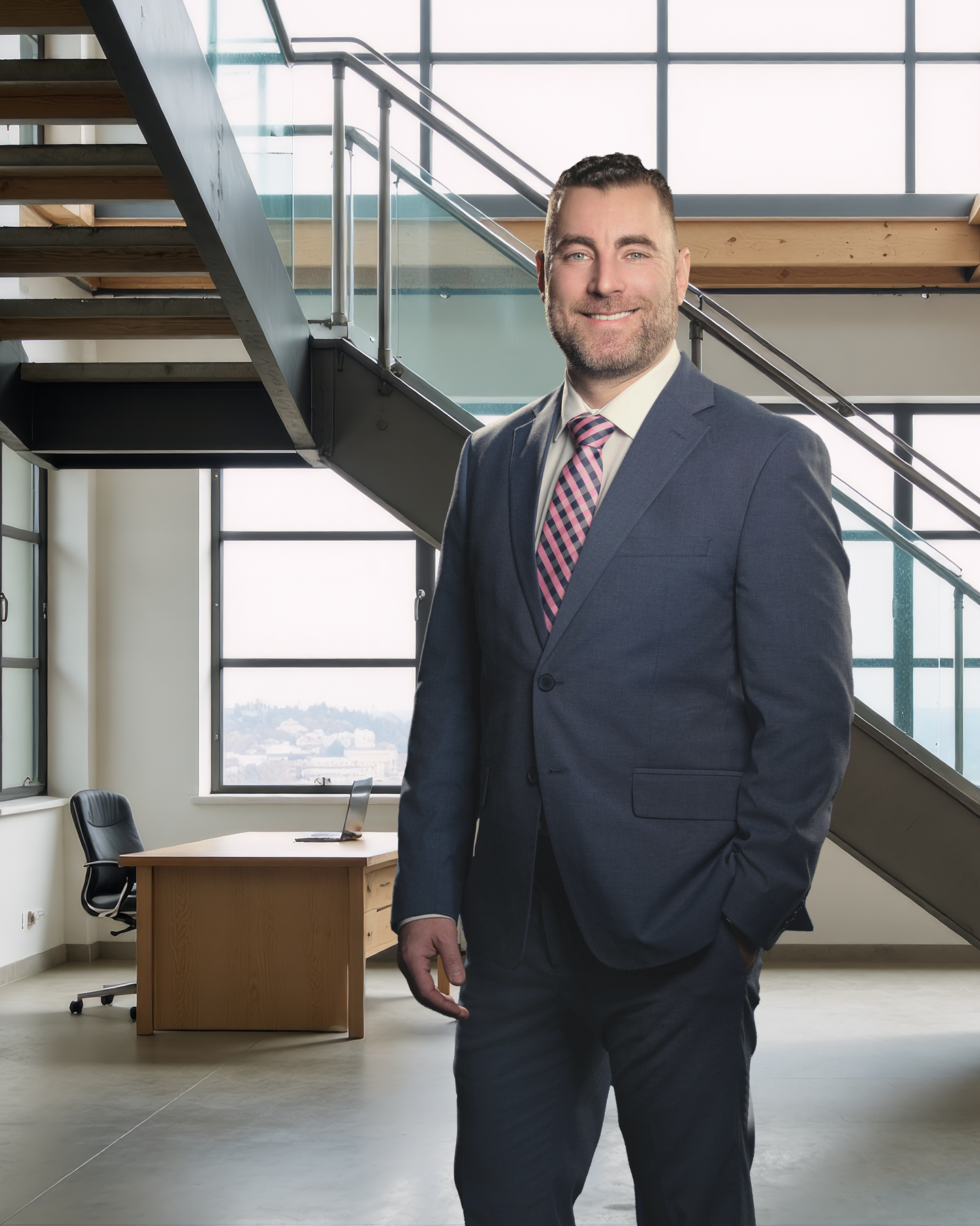 A man in a blue suit with a pink and blue striped tie standing in a modern office with large windows and a staircase. In office headshot and branding photographer in Maryland, PA, VA and NYL Washington D.C. 