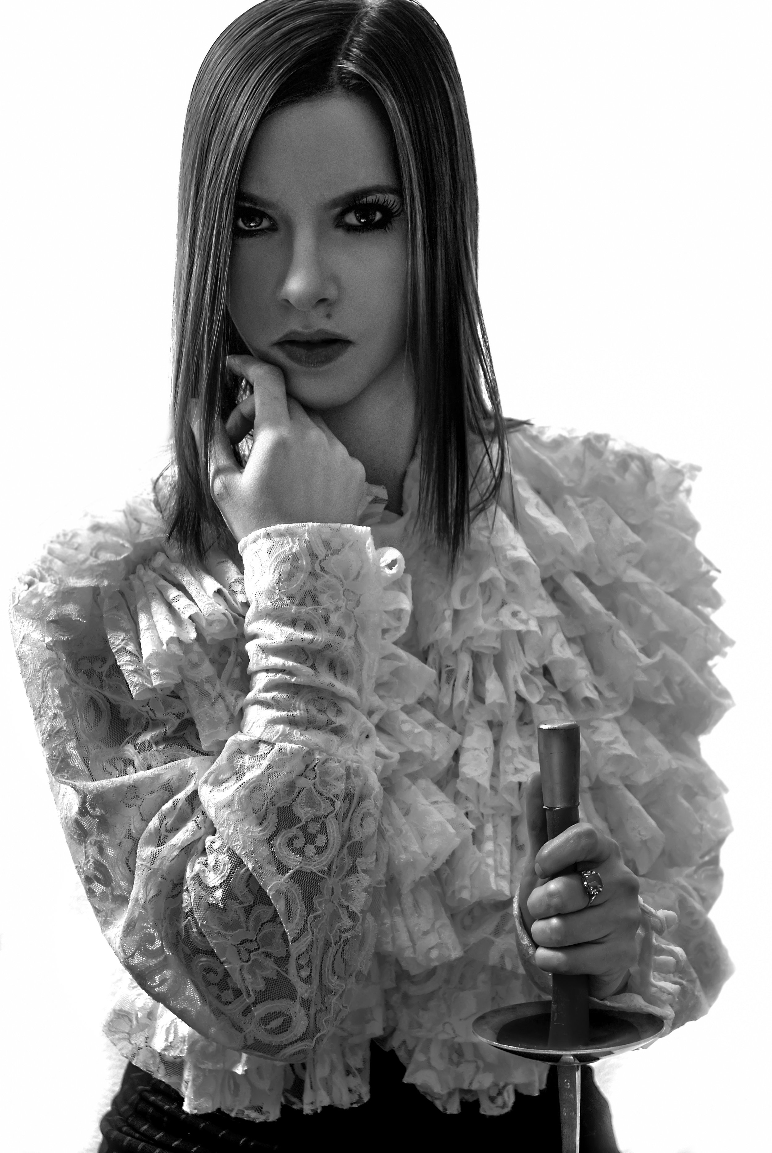 A woman with straight hair, wearing a ruffled lace blouse, holding a sword and touching her face with her other hand in a black and white photo. Best-Fashion-Portrait-Commercial-Business-Headshots-Corporate- photography-Maryland-Washington D.C.-Penns