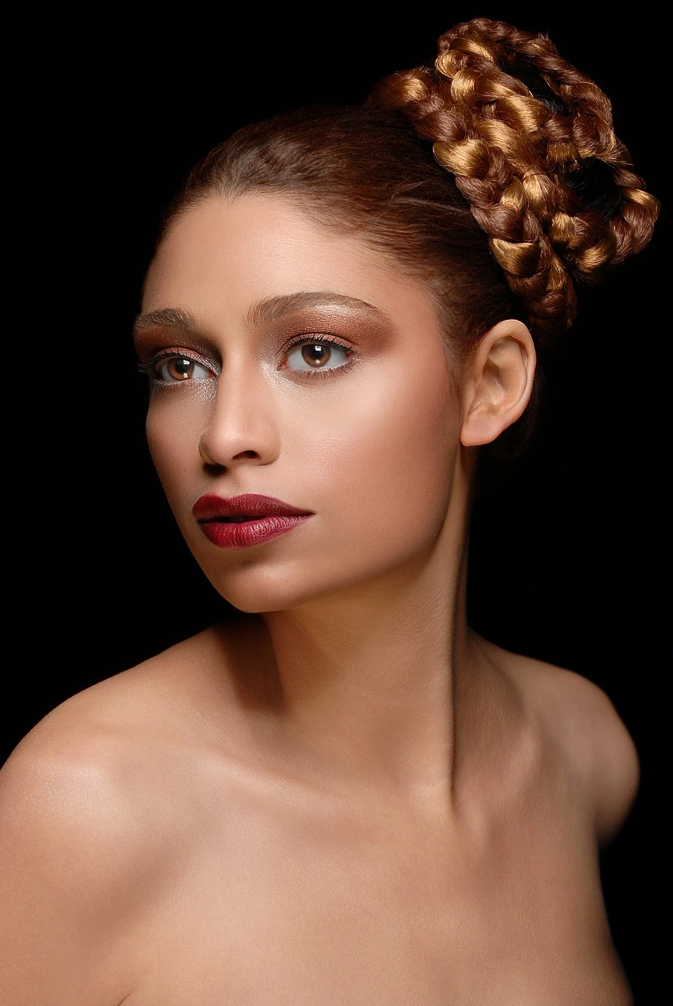 Portrait of a woman with elaborately braided updo hairstyle, wearing makeup, with bare shoulders against a black background. Best-Fashion-Portrait-Commercial-Business-Headshots-Corporate- photography-Maryland-Washington D.C.-Pennsylvania-Virginia