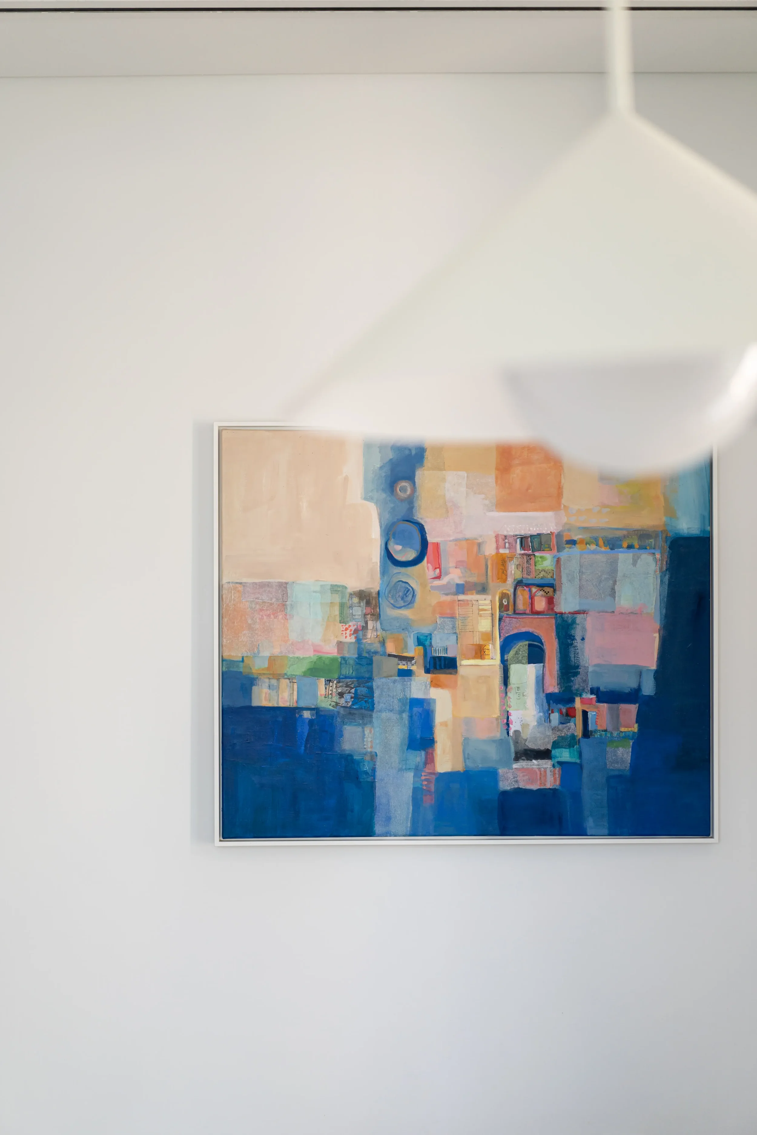 Abstract colorful painting on a white wall, partially obscured by an out-of-focus white object in the foreground.
