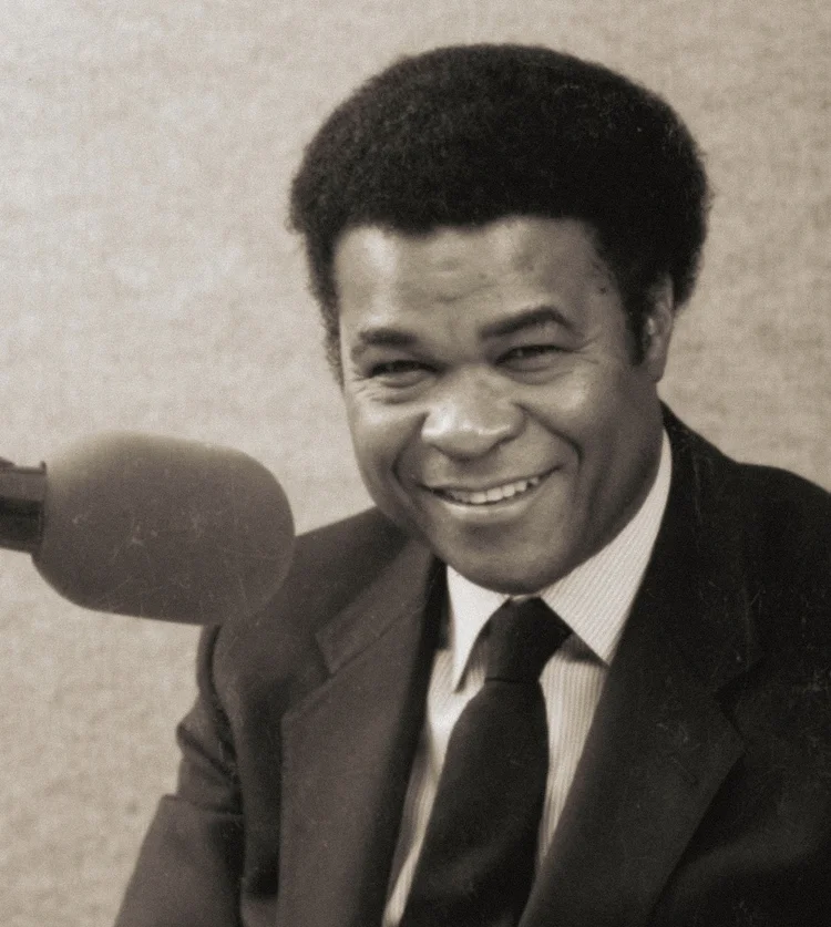 Ken Jones smiling in front of a radio microphone.