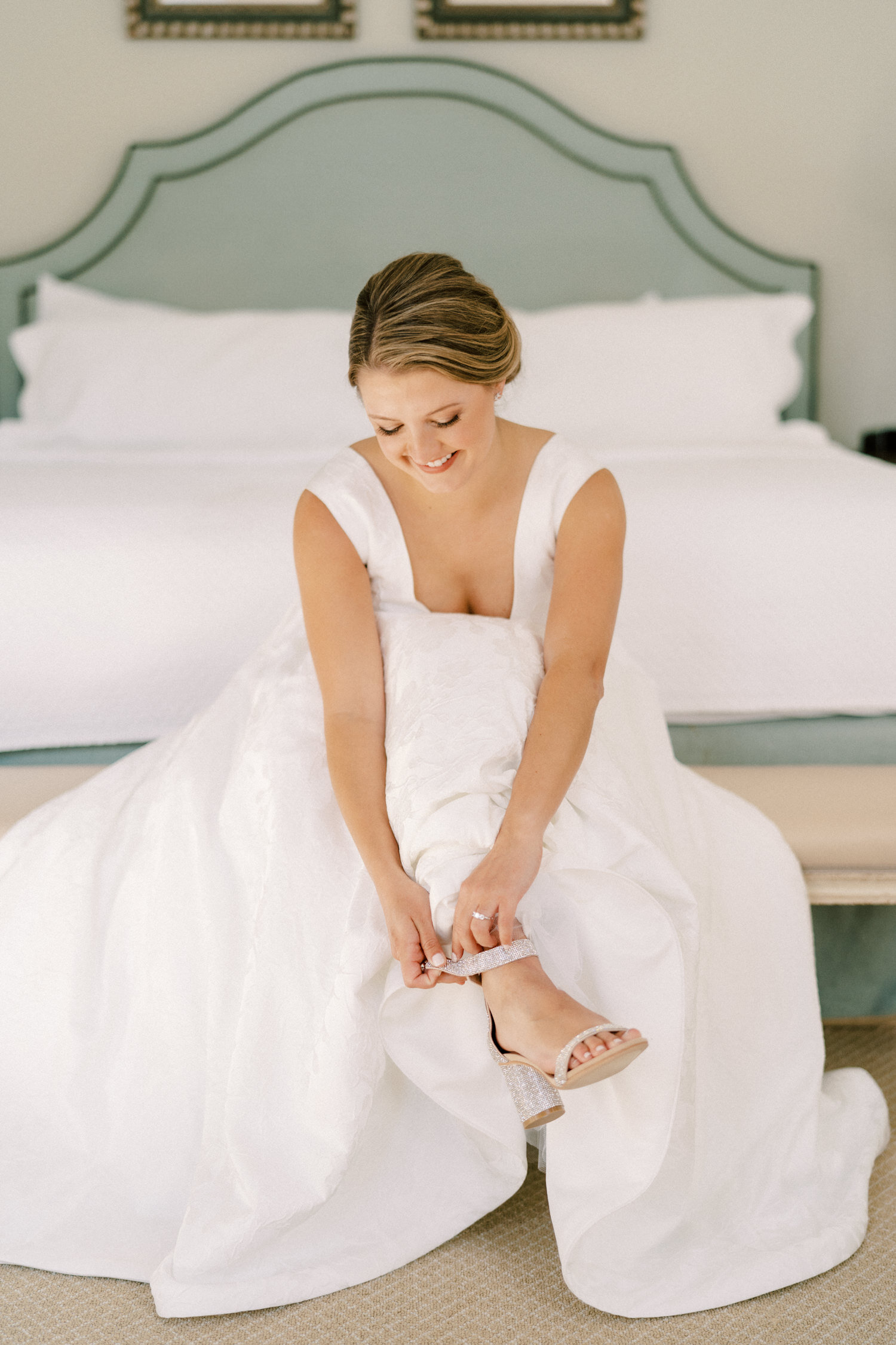 bride in gown putting on shoes