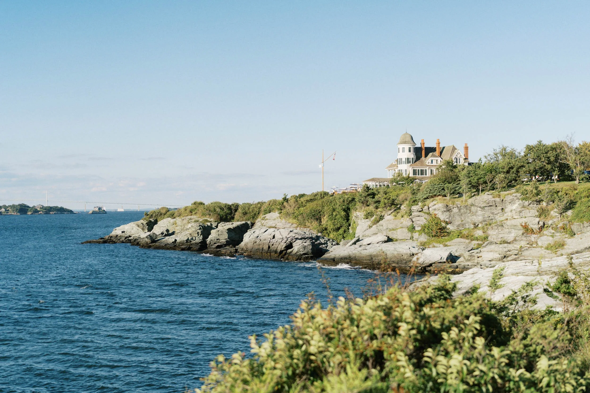A scenic view of a house on a rocky coast overlooking a blue body of water during daytime.