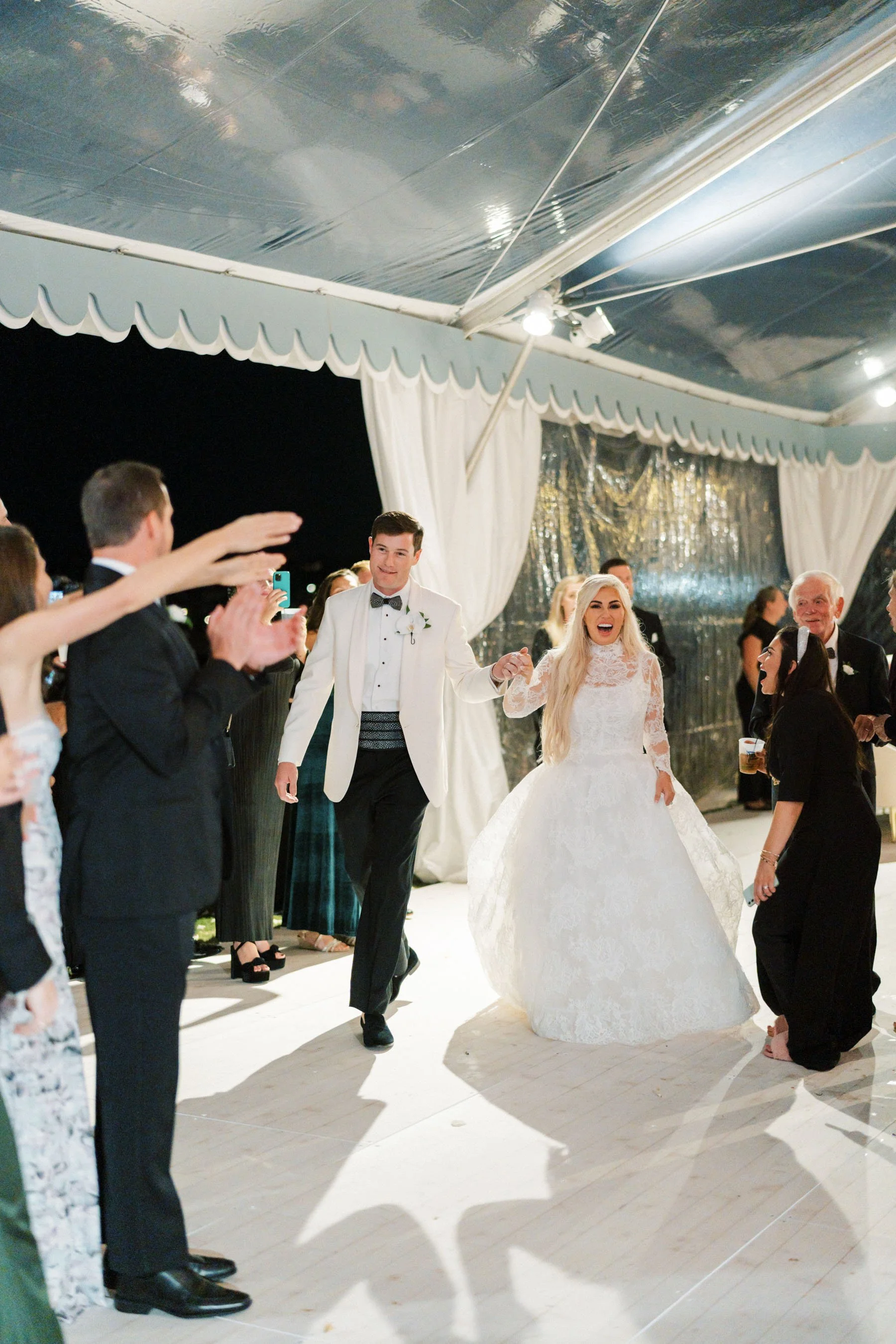 Bride and groom dancing at their wedding reception, surrounded by guests.