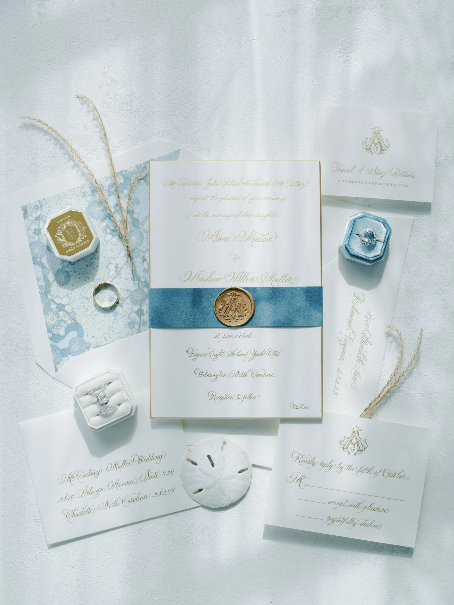 Wedding invitation suite with rings, wax seals, and stationery on a white surface.