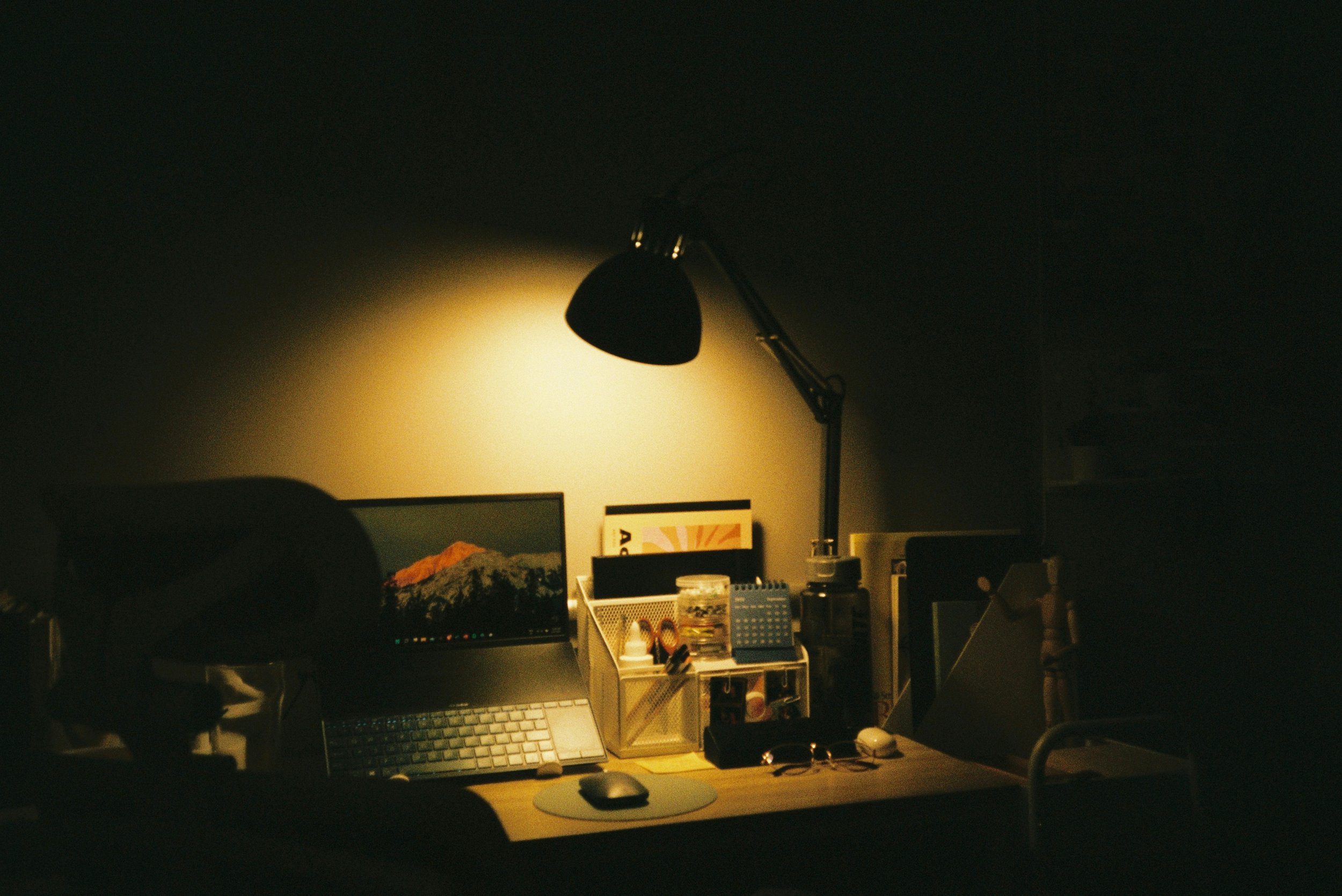 Dimly lit desk with laptop and lamp representing high achieving clients with anxiety