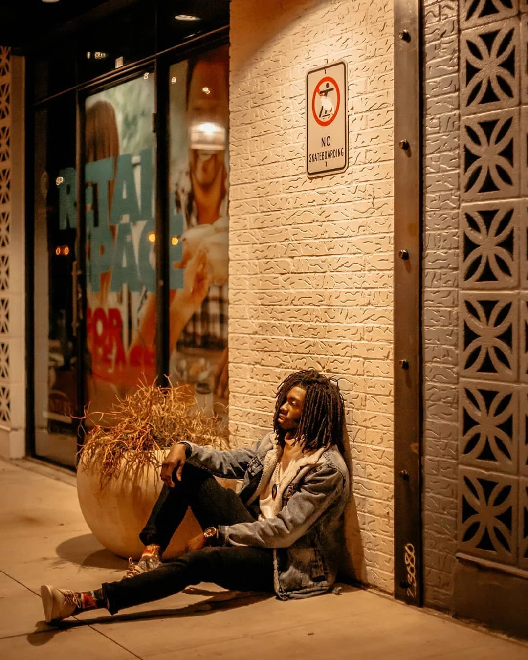 man sits on ground under light with leg propped up