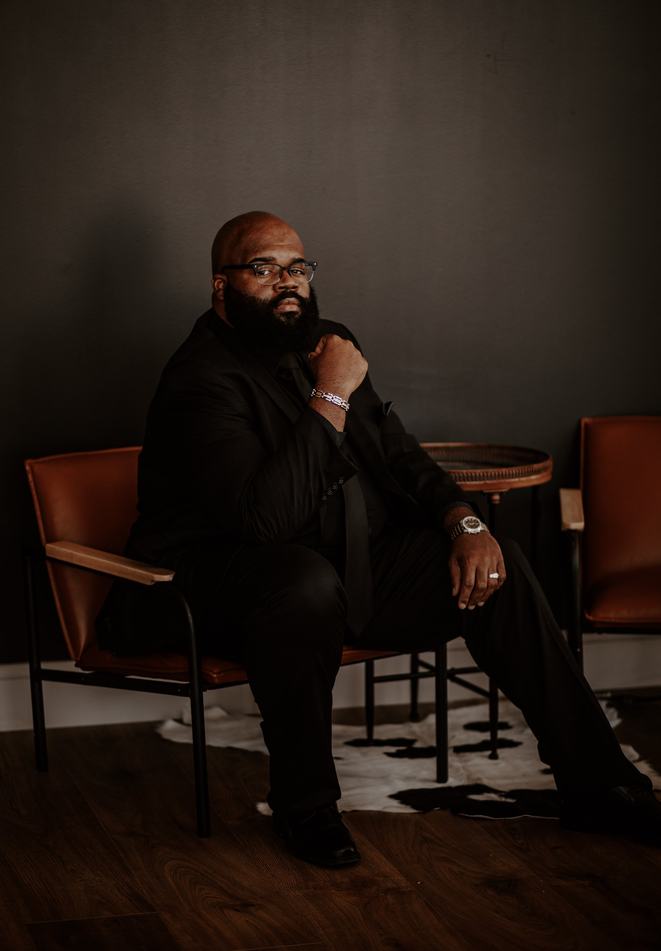 man sits in chair with hand on chin