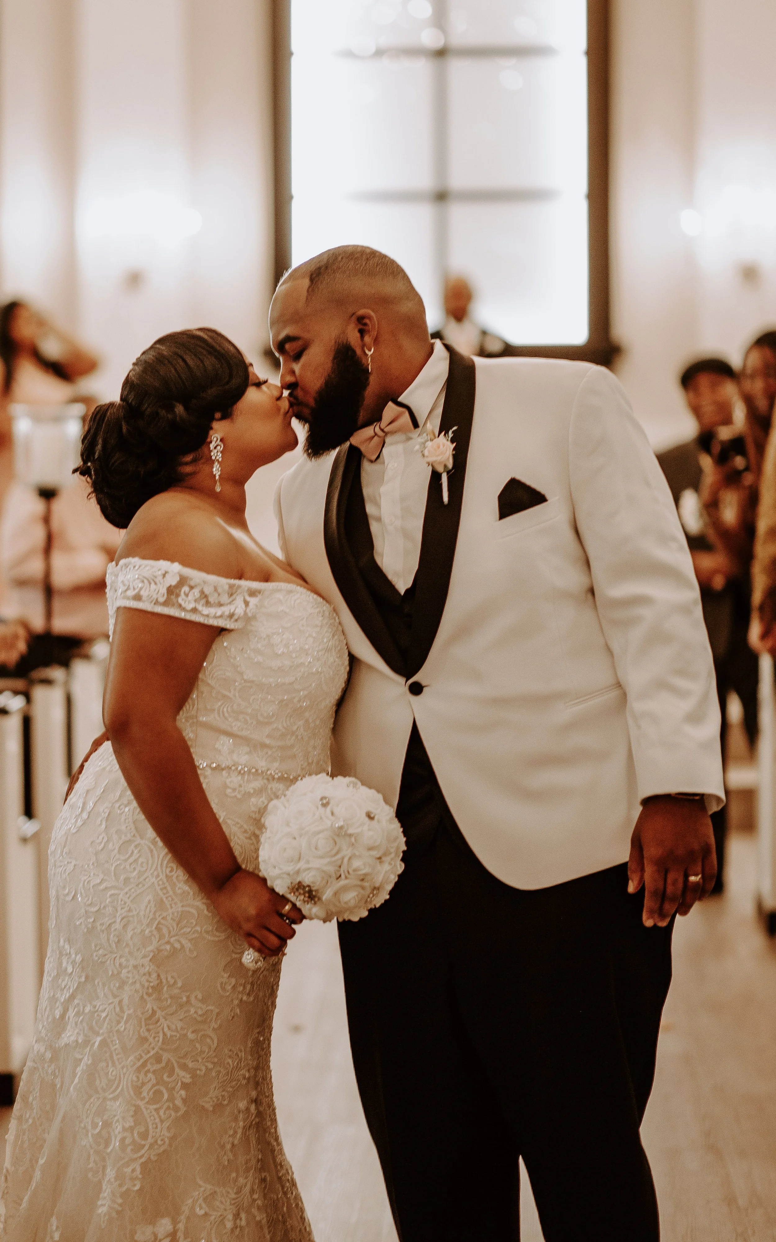 man and woman kiss in church aisle at wedding