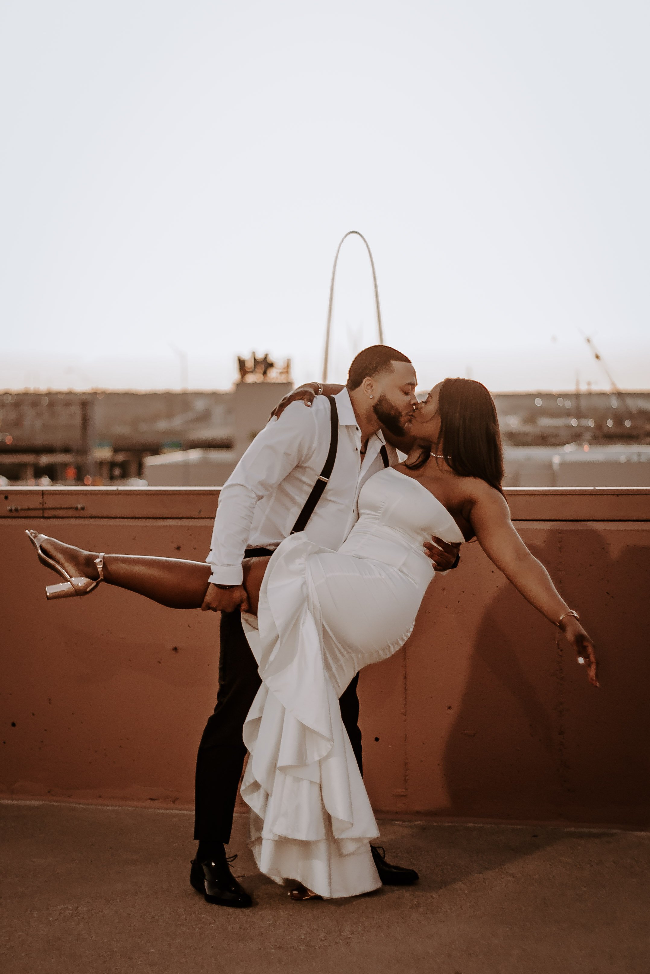 couple kissing on rooftop in front of bridge