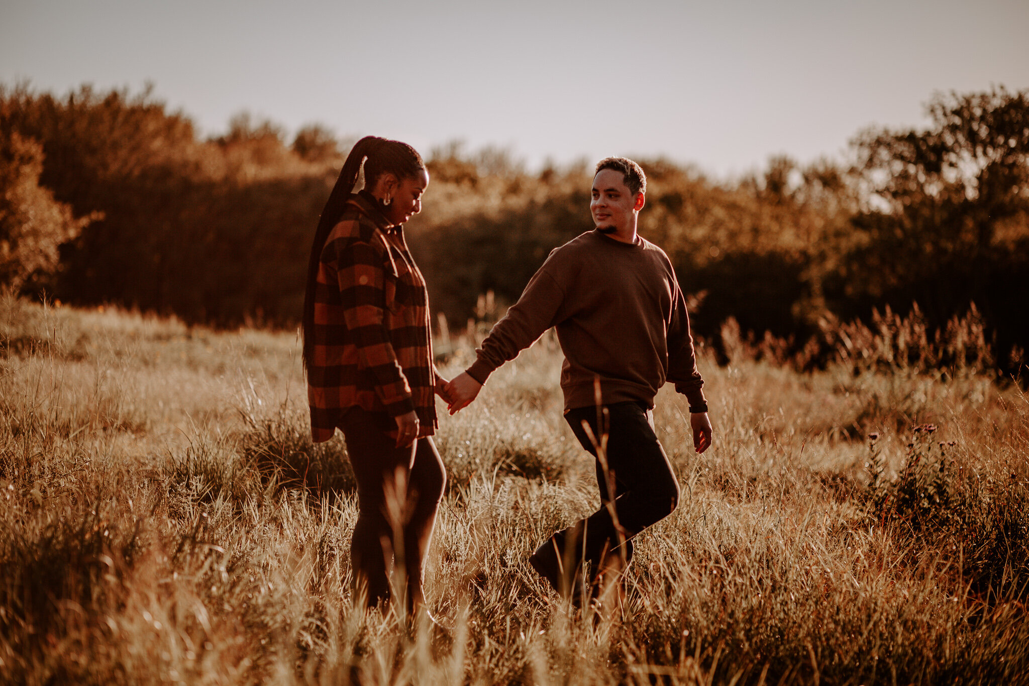 man and woman walk in field of fall grass
