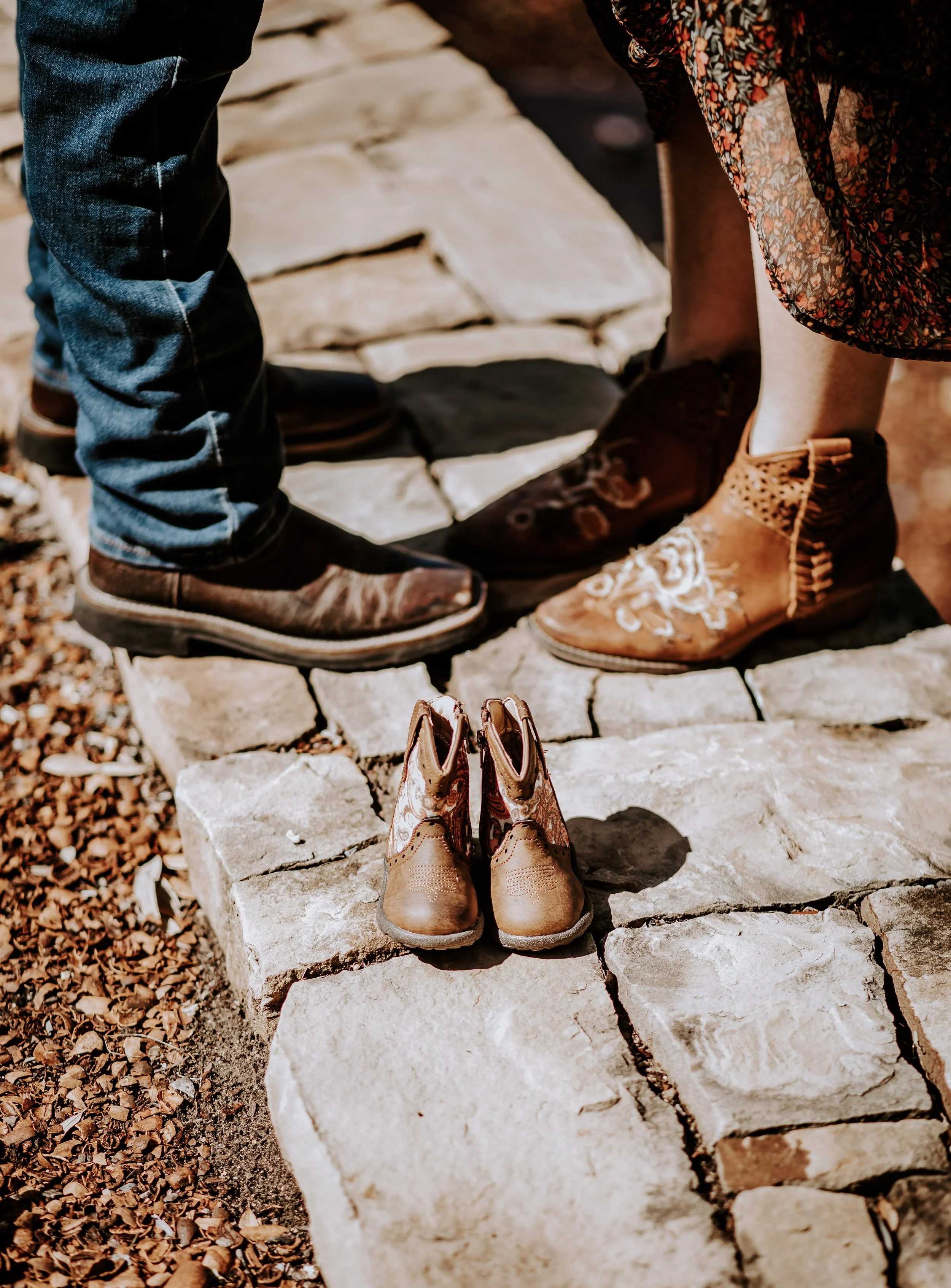 man and woman stand toe to toe with child sized pair of boots in front