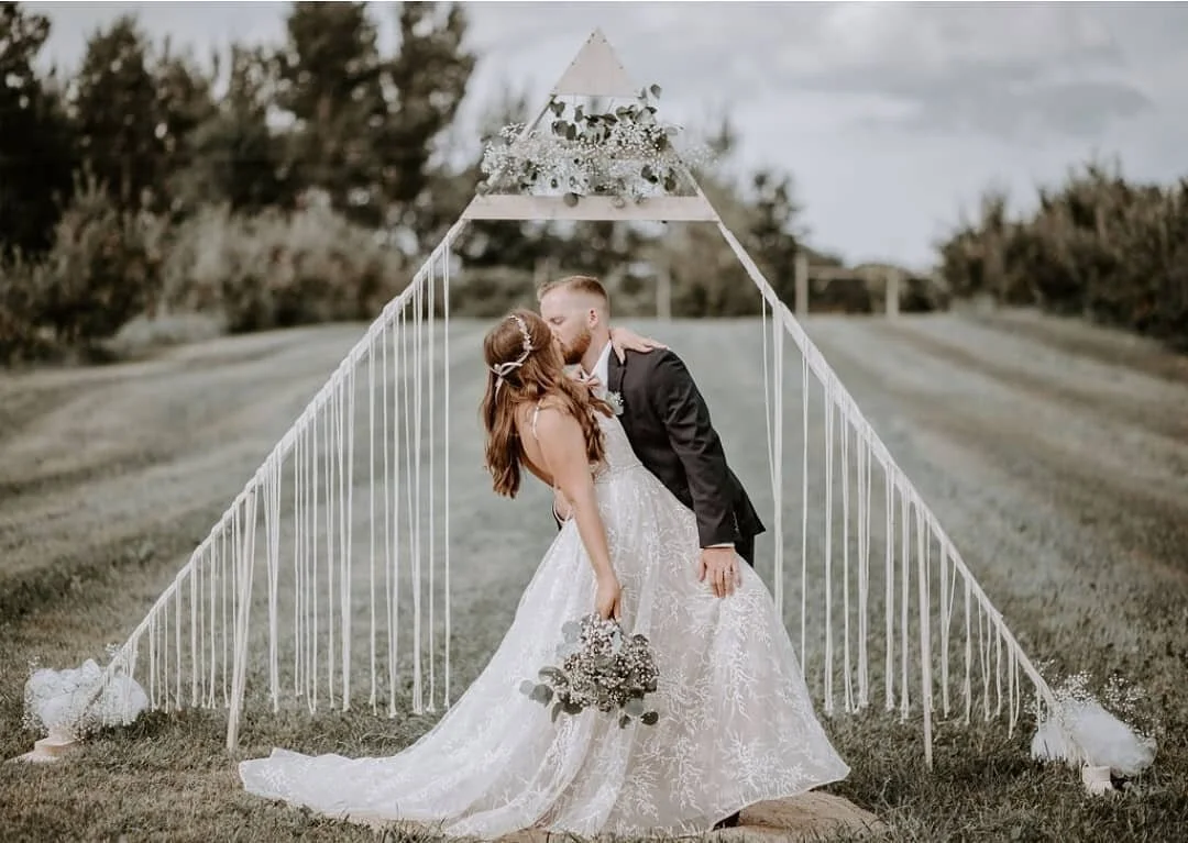 woman and man kiss in front of wedding backdrop