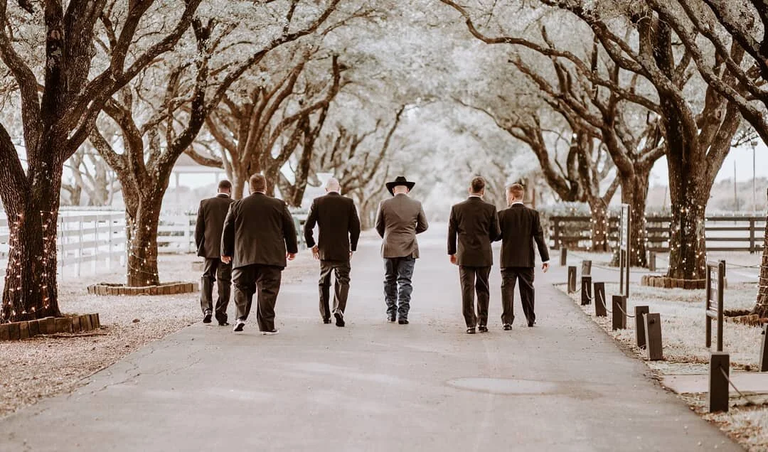 six men walk down driveway lined with trees