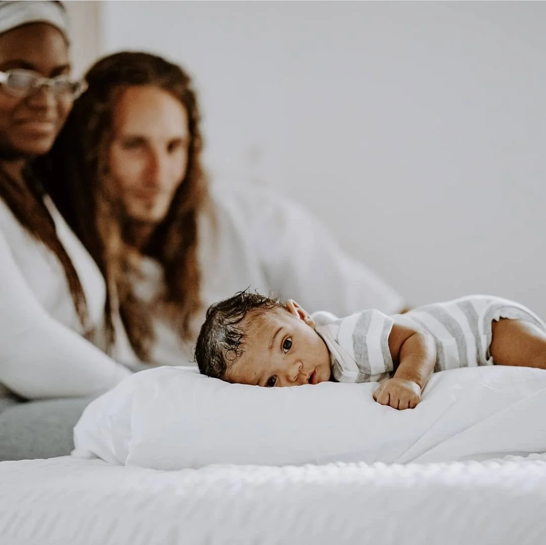 man and woman looking at baby on bed