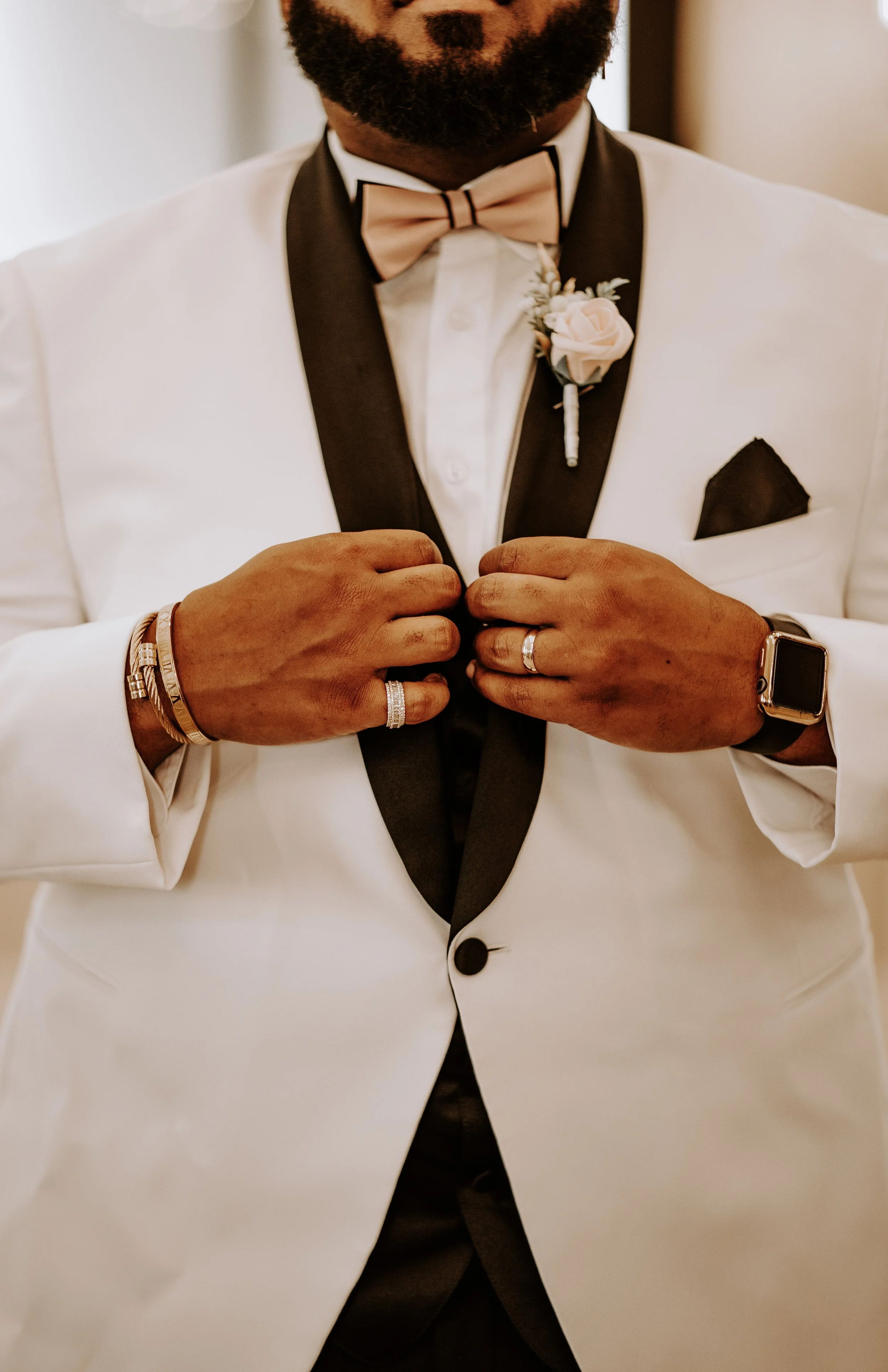 man holding his collar to display bowtie and rings