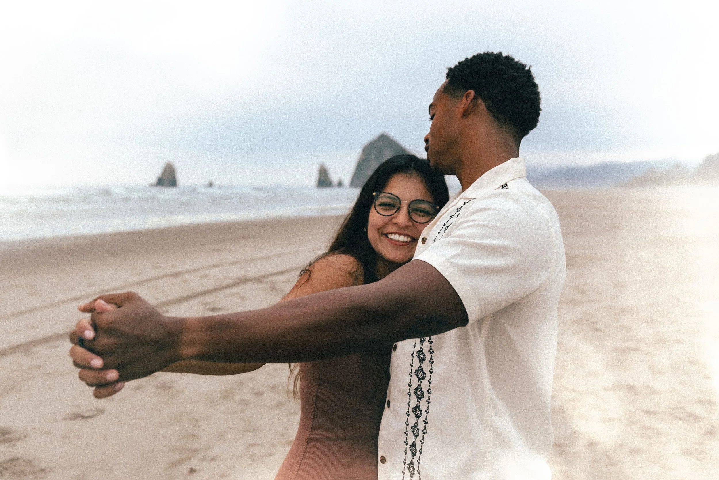 Couple holding hands on the beach in Oregon during an engagement session by Abigail Janelle Photography