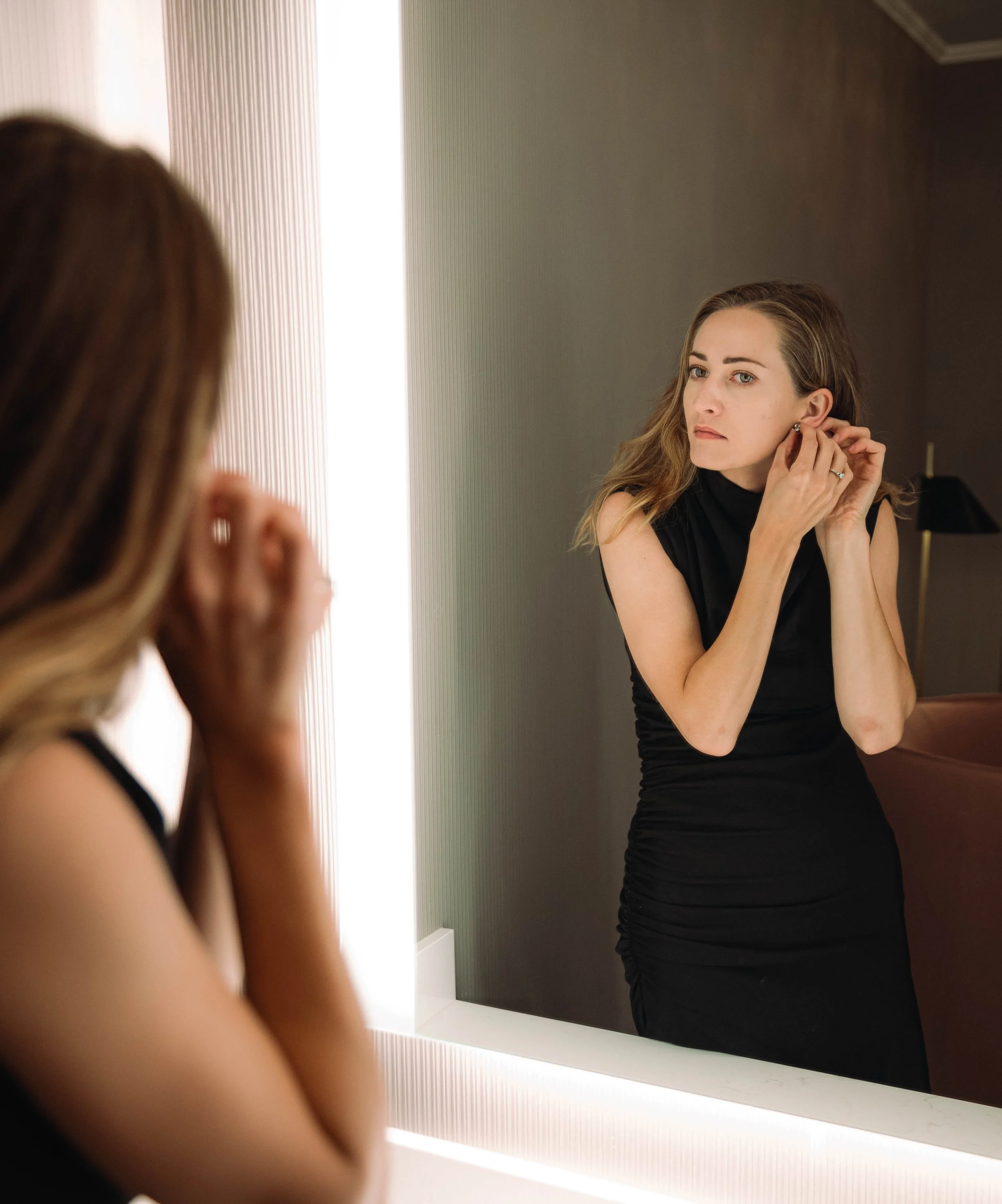 Reflection of a women getting ready in the mirror for her rehearsal dinner in a Portland, OR hotel