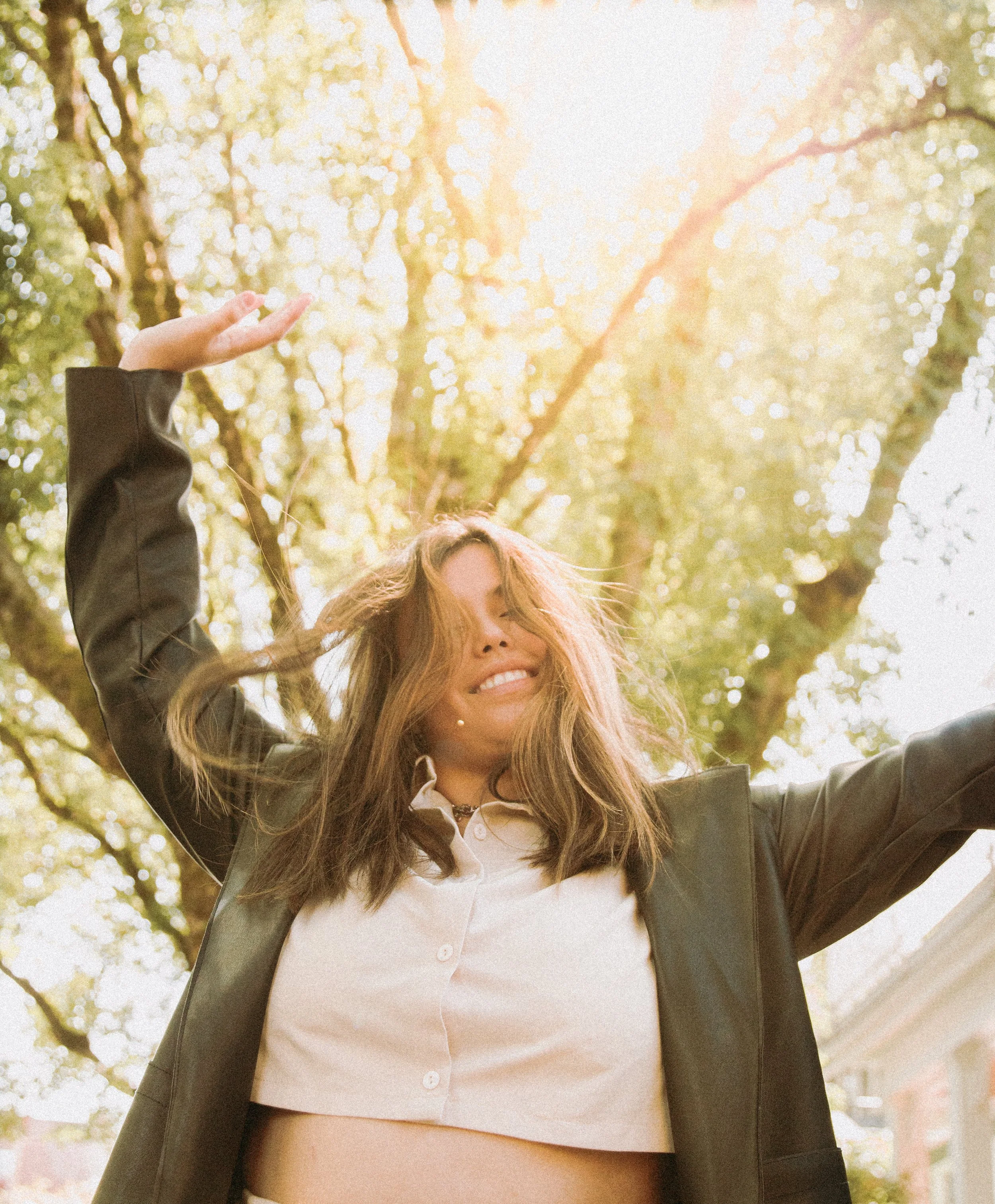 Woman smiling and throwing hands in the air in downtown Portland, OR by Abigail Janelle Photography