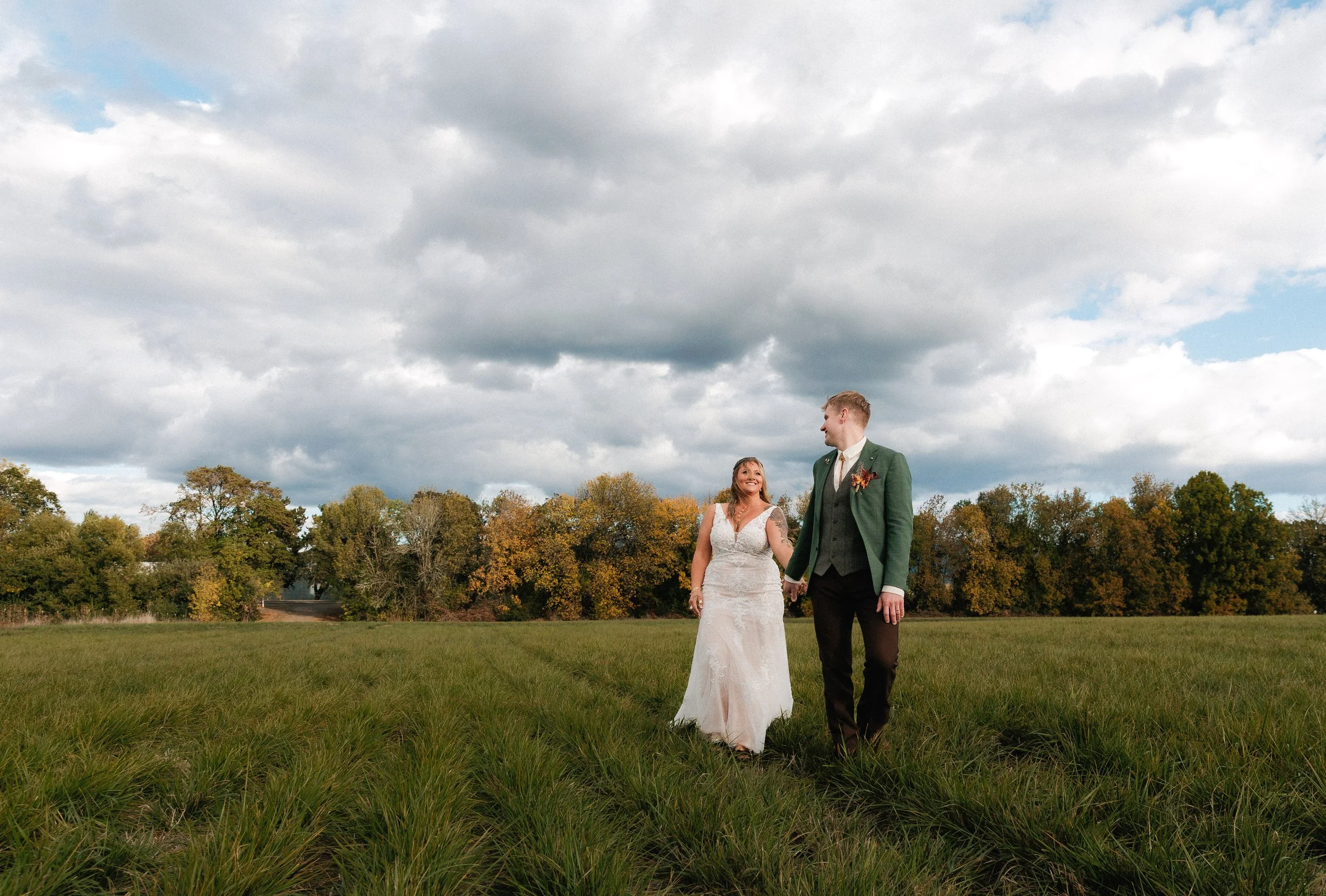 Newlywed couple walking through a field under dramatic moody clouds after their oregon wedding