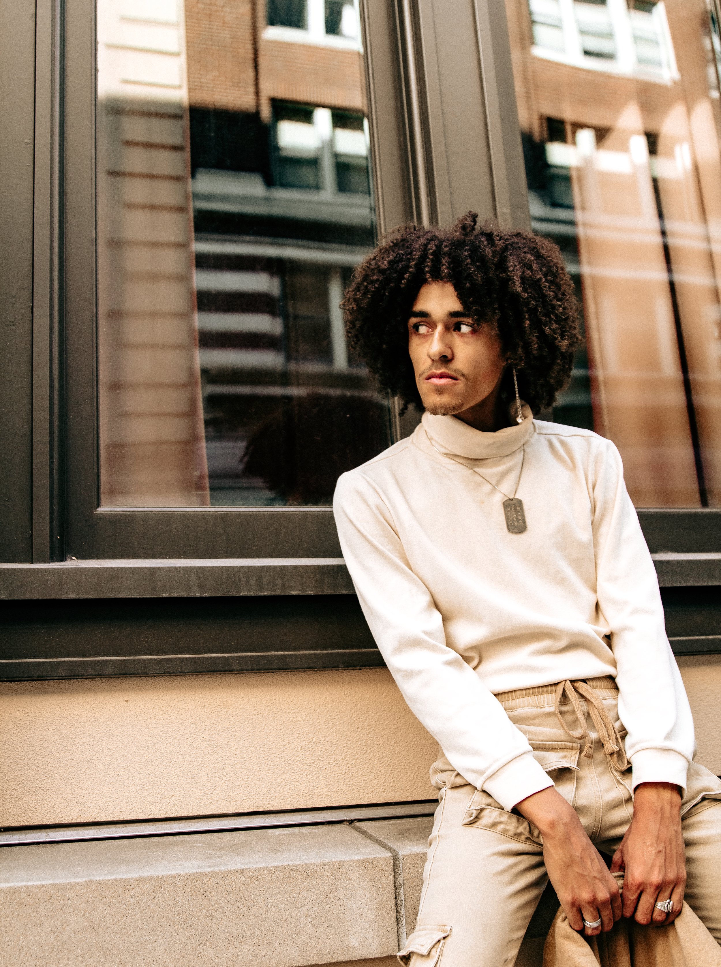 Man sitting on a wall in downtown Portland, OR during a portrait session by Abigail Janelle Photography