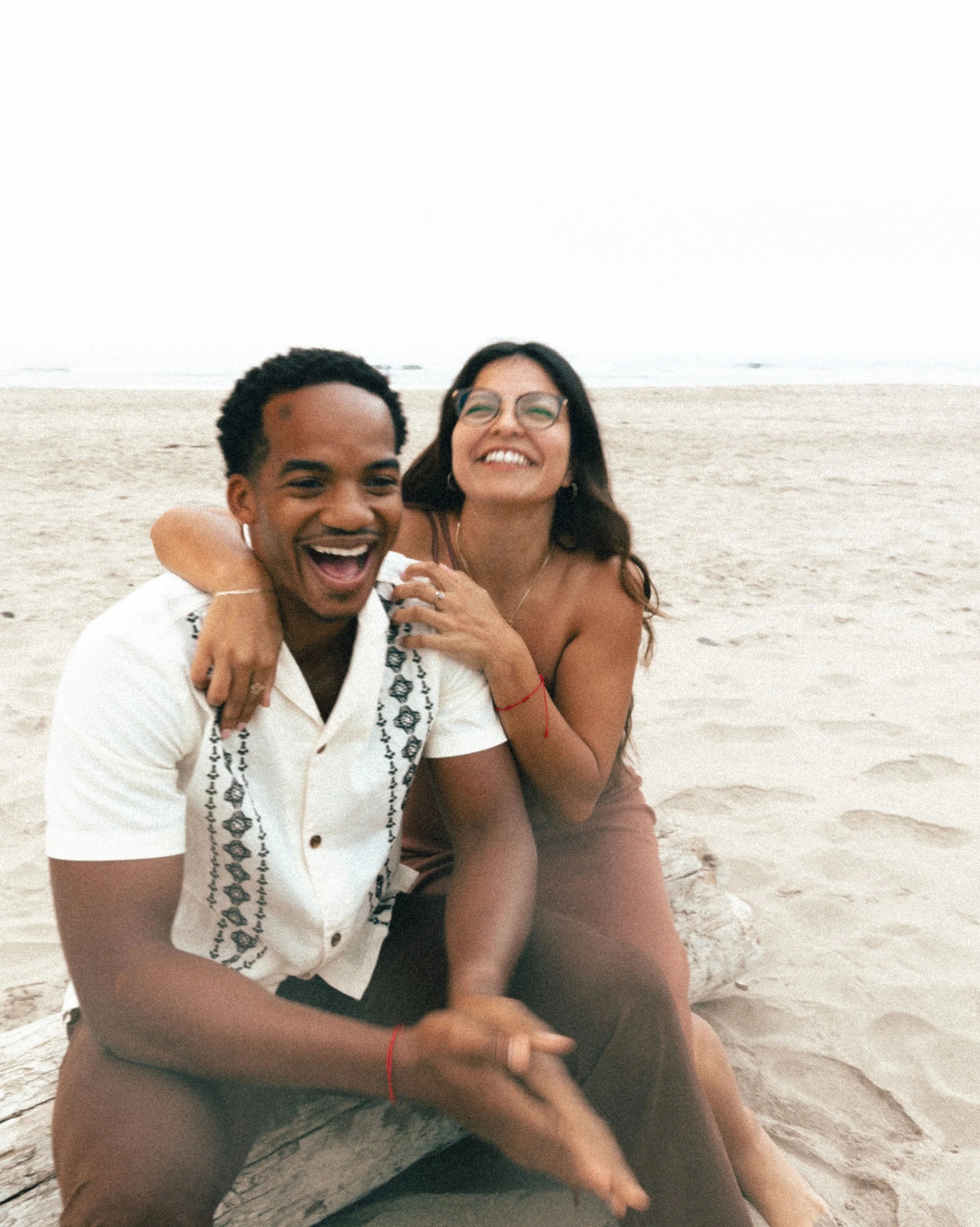 Couple laughing on the beach during their engagement session on the Oregon Coast