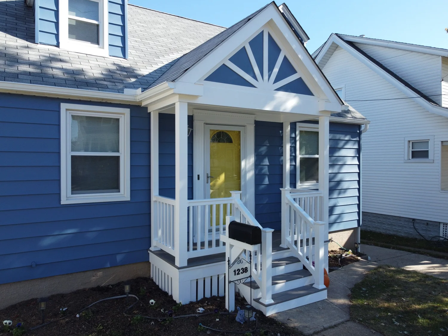 Finished blue front porch addition with white railings and lattice skirt