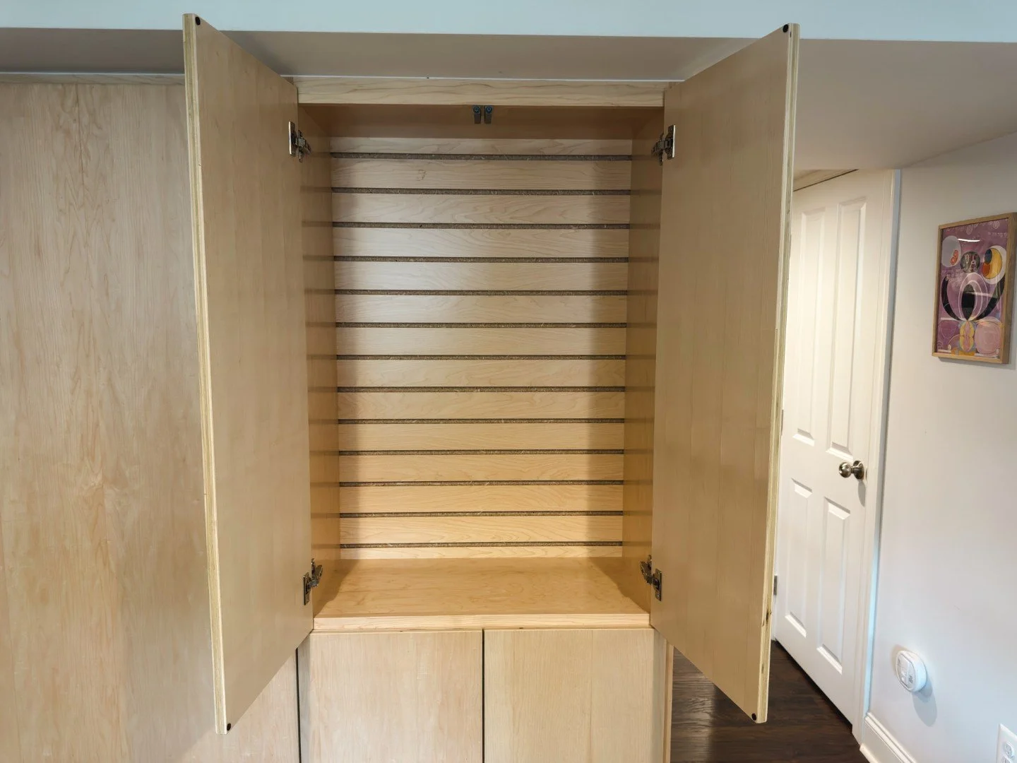 Hidden slatwall system inside a basement storage cabinet