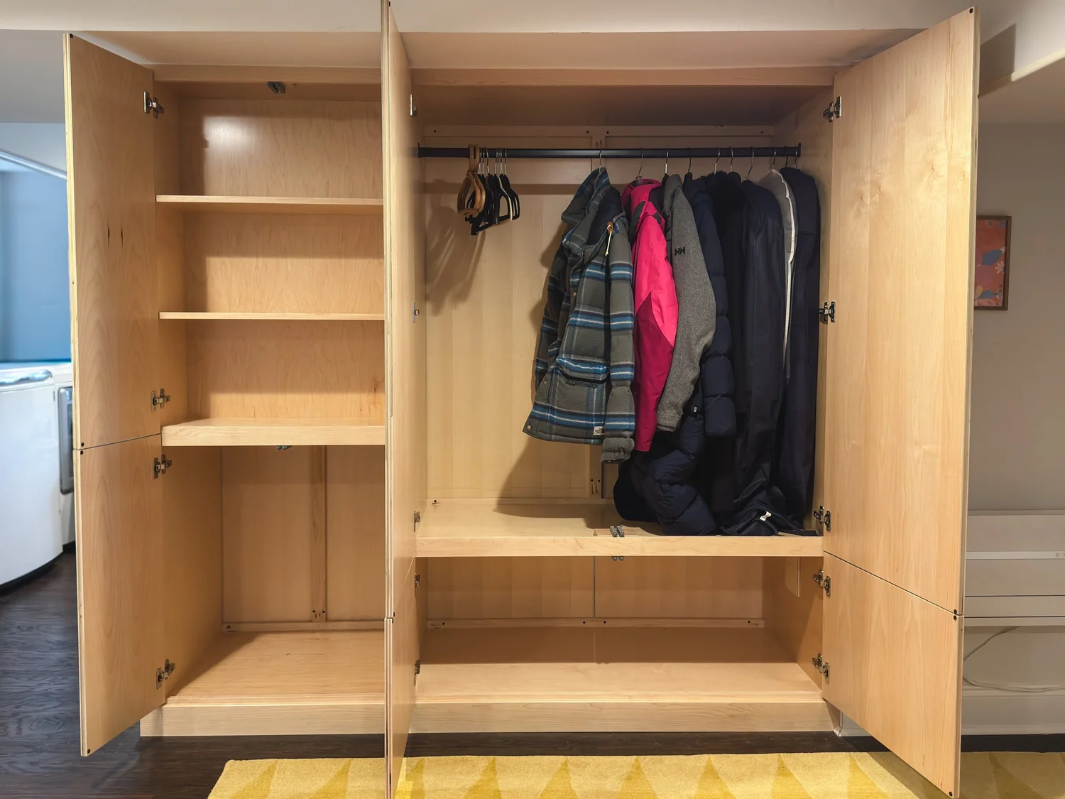 Open basement built-in with coat rod, shelves, and lower bin storage