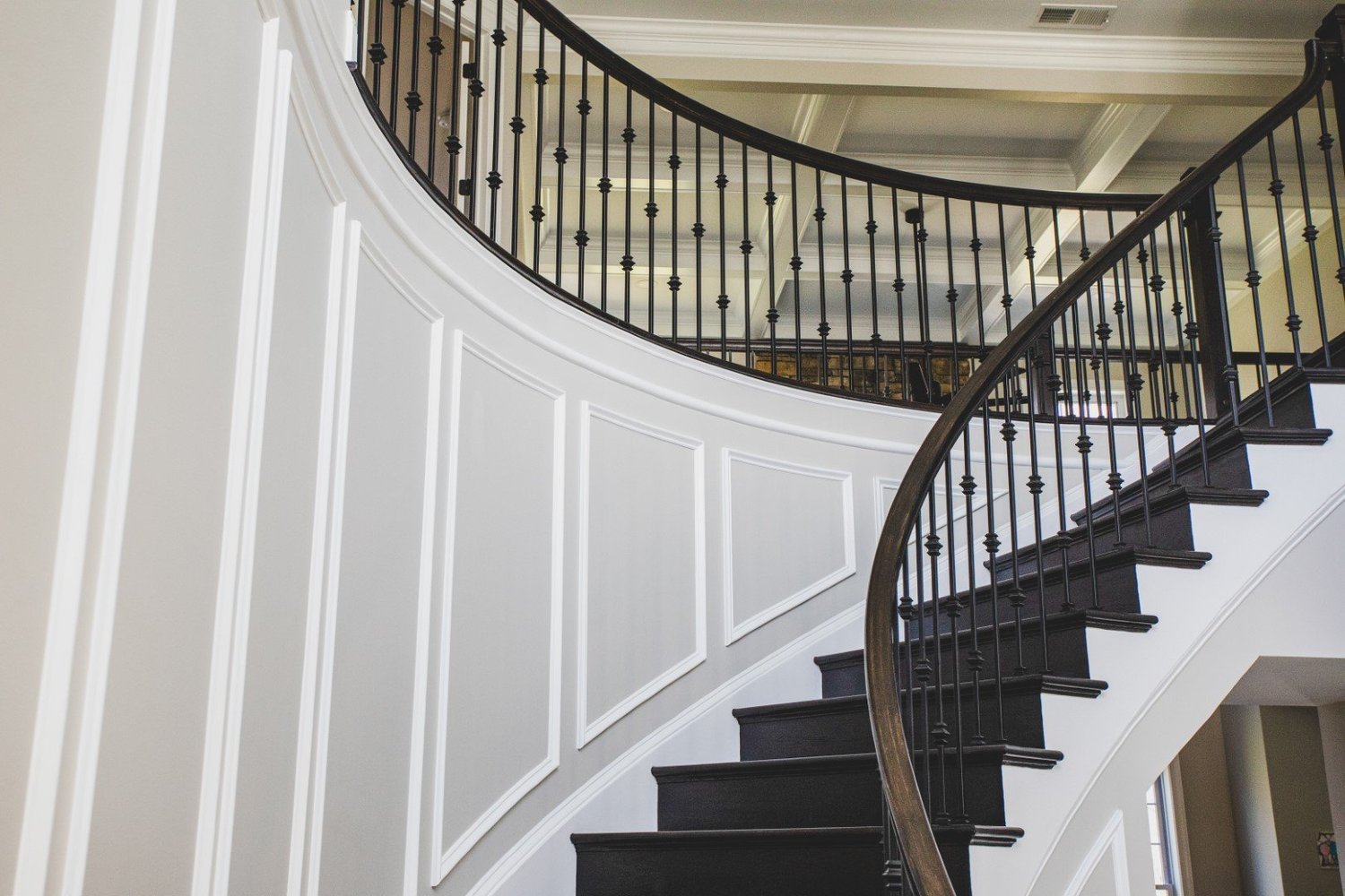 Shadow box trim guiding upward along a curved staircase
