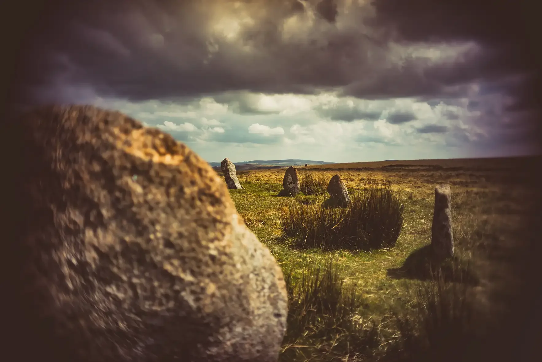 Ancient stone circle in a grassy landscape under ominous dark clouds
